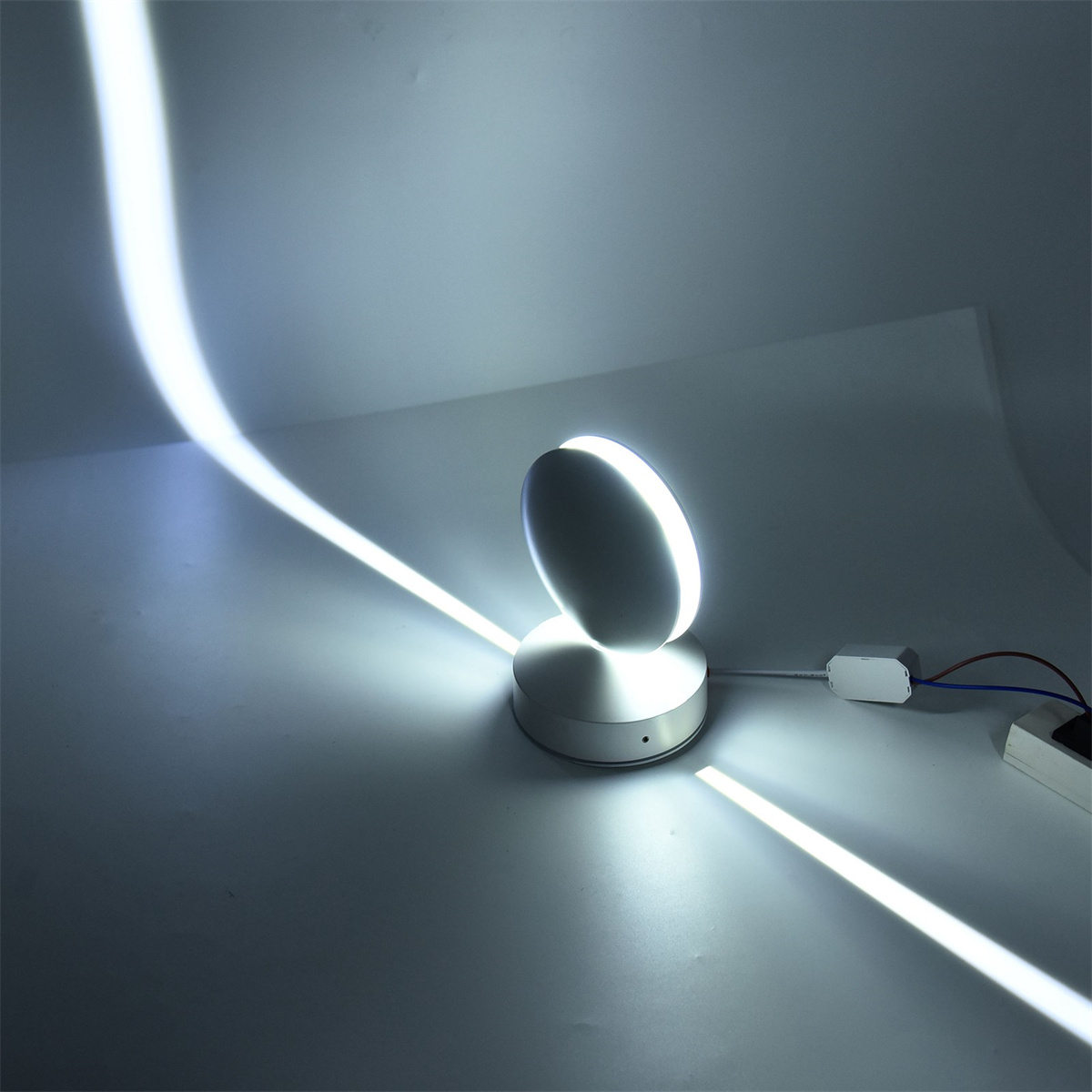 Eine moderne weiße und silberne Lampe, die ein weißes, gerichtetes Licht aussendet.