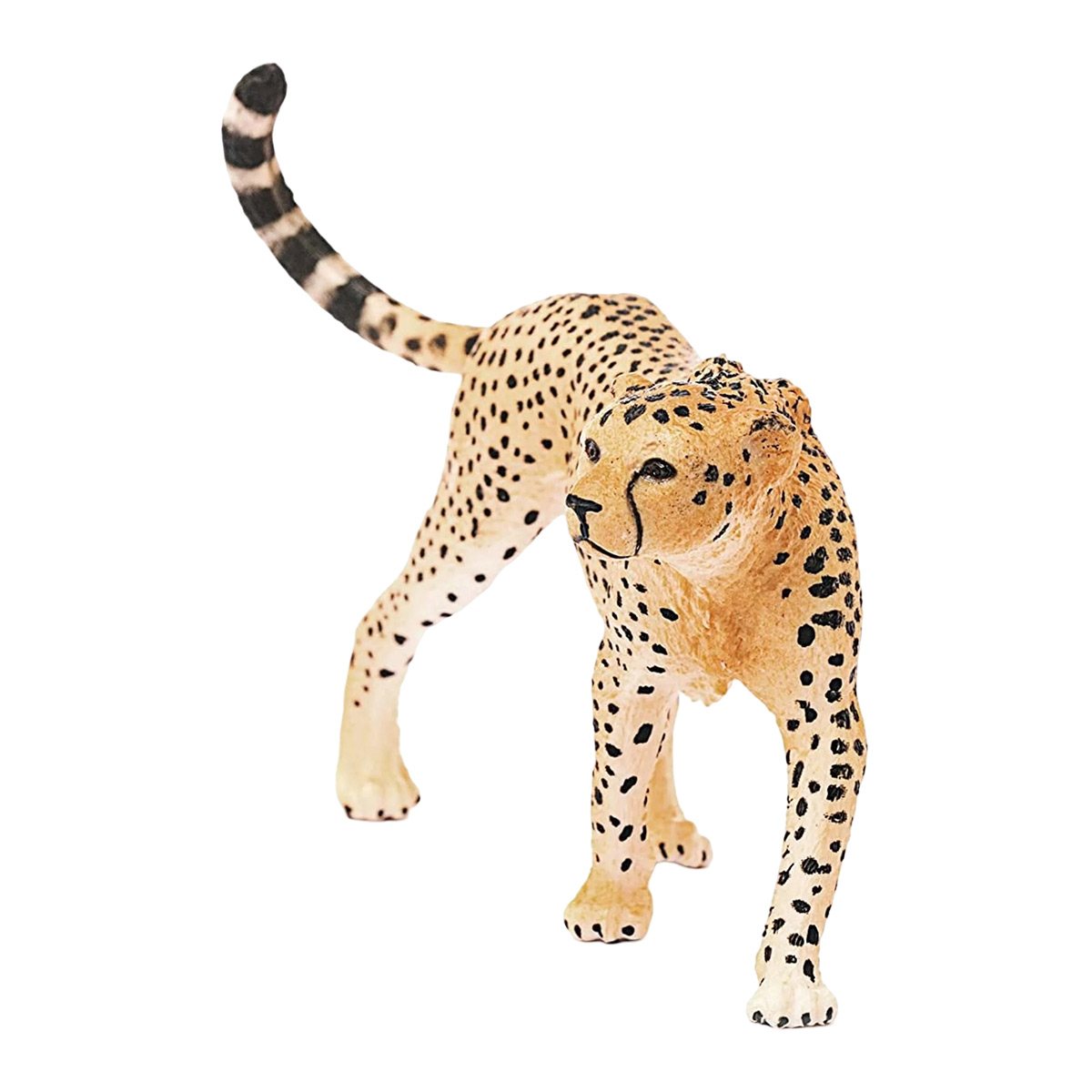 Spielzeug-Gepard. Gelbes Fell mit schwarzen Flecken. Steht auf weißer Oberfläche. Schwanz gestreift.