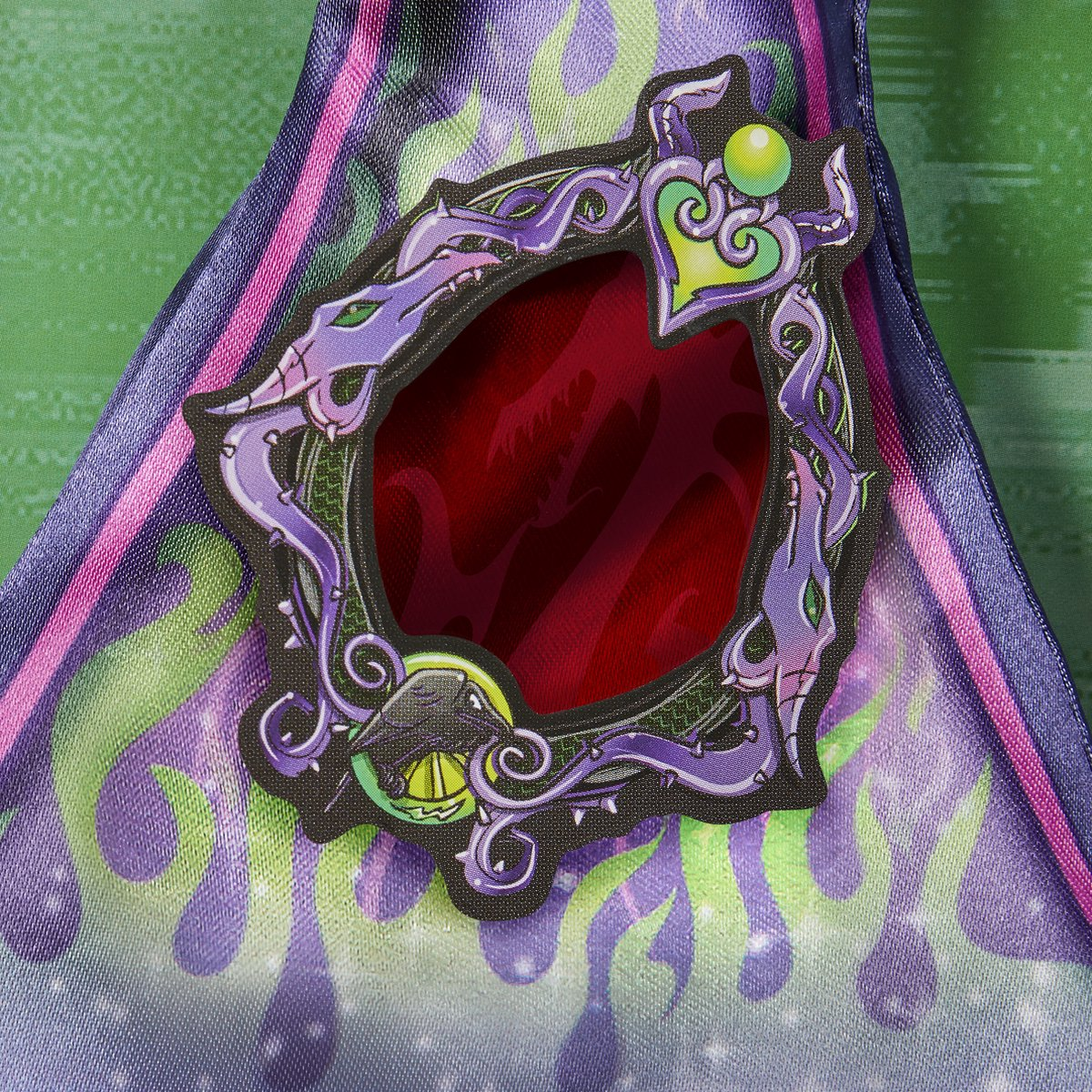 Ozdobna odznaka z czerwonym środkiem otoczonym fioletowymi i zielonymi detalami.