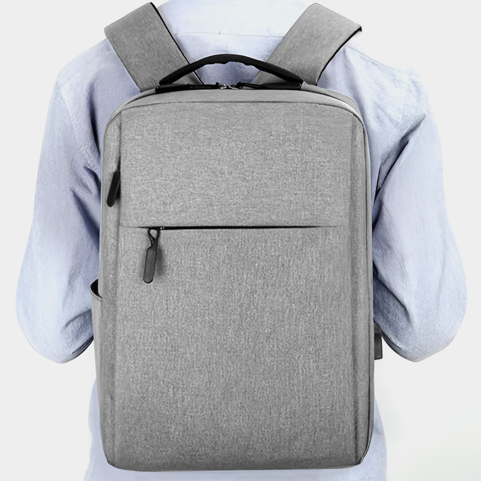Grauer Rucksack mit schwarzem Reißverschluss und Trägern, von hinten betrachtet. Ein Mann trägt hellblaues Hemd.