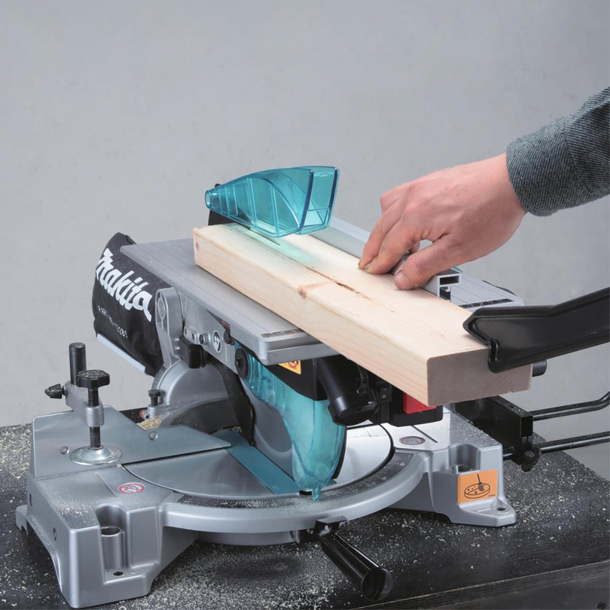 Eine Person schneidet mit einer Makita-Gehrungssäge ein Holzbrett.