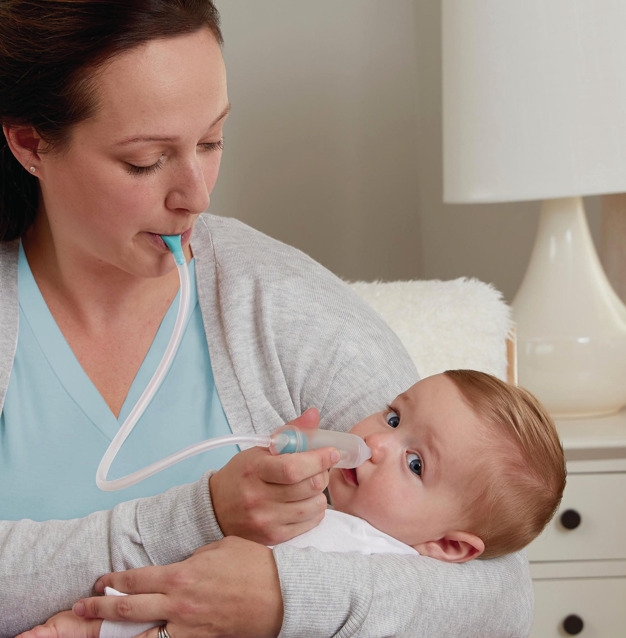 Eine Mutter benutzt einen Nasensauger bei einem Baby, das sie im Arm hält.