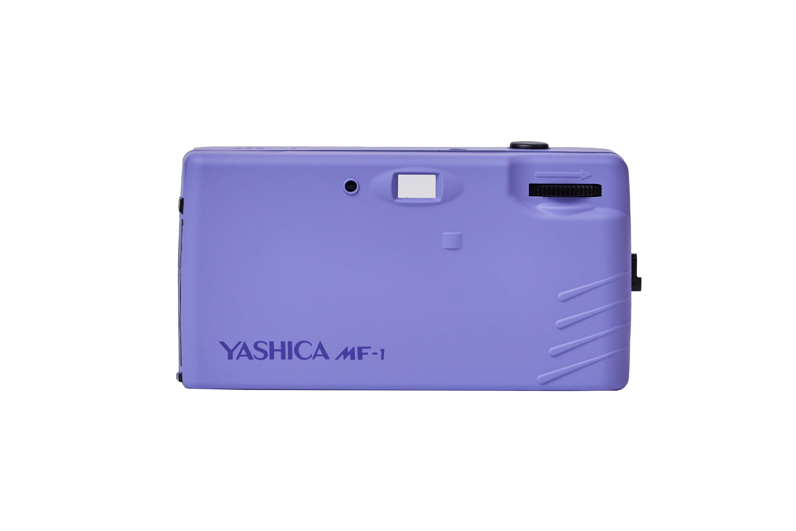 Fotocamera viola Yashica MF-1. Sfondo bianco. Vista posteriore, nome scritto sopra.