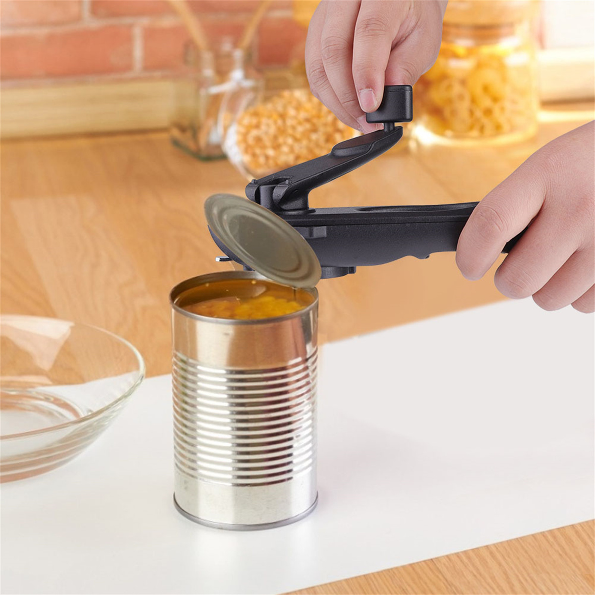 Hände, die einen Dosenöffner verwenden, um eine Dose mit Essen zu öffnen, auf einer Holzoberfläche mit anderem Essen.