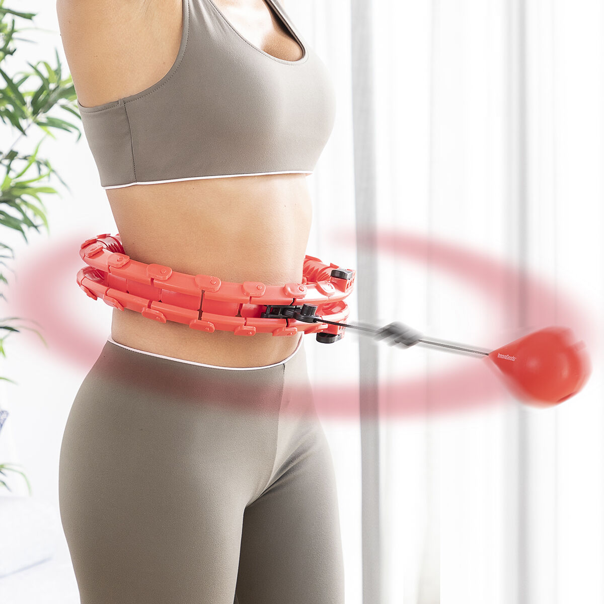 Una persona haciendo ejercicio con un hula hoop con peso, con un aro rojo y fondo blanco.