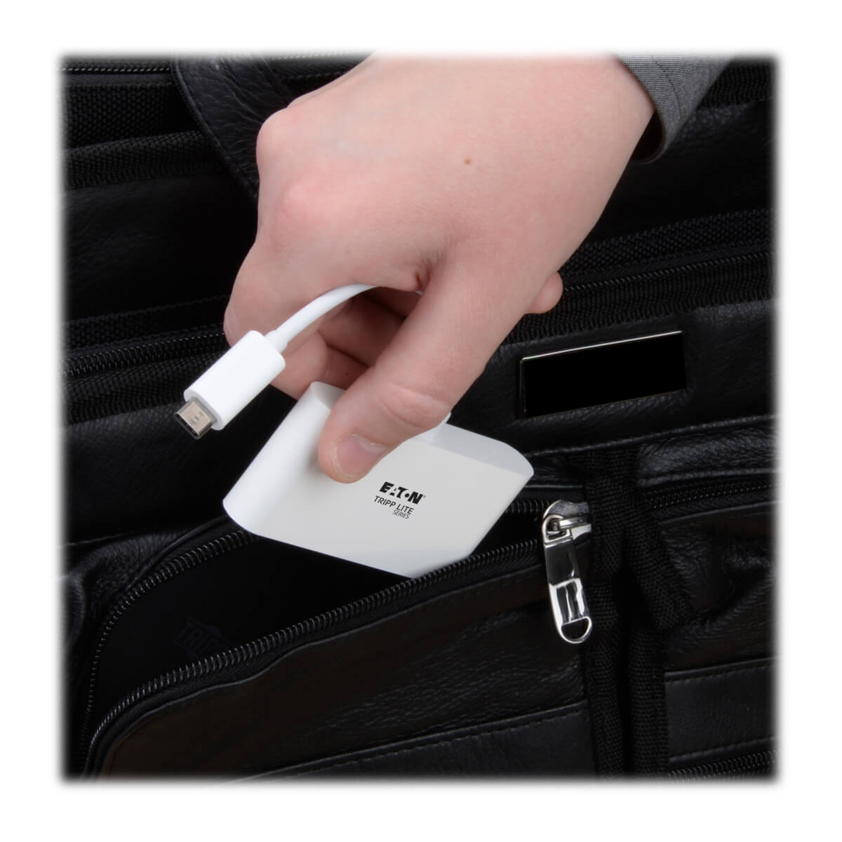 Mano che tiene un hub USB bianco, lo mette in una borsa nera, con il logo EATON TRIPP LITE.