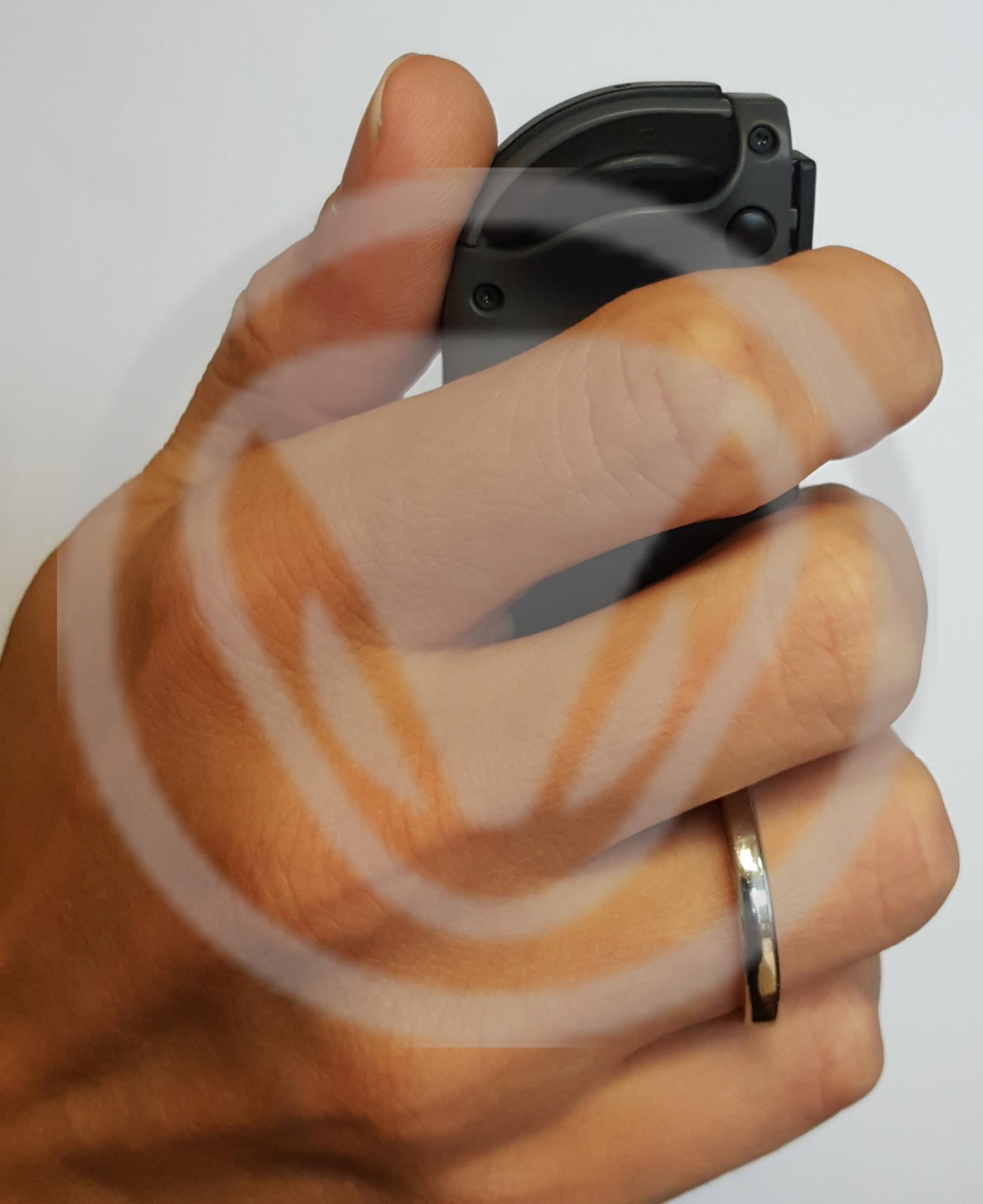 Eine Hand hält ein schwarzes Objekt, möglicherweise ein Werkzeug. Ein Ehering am Ringfinger. Logo überlagert.