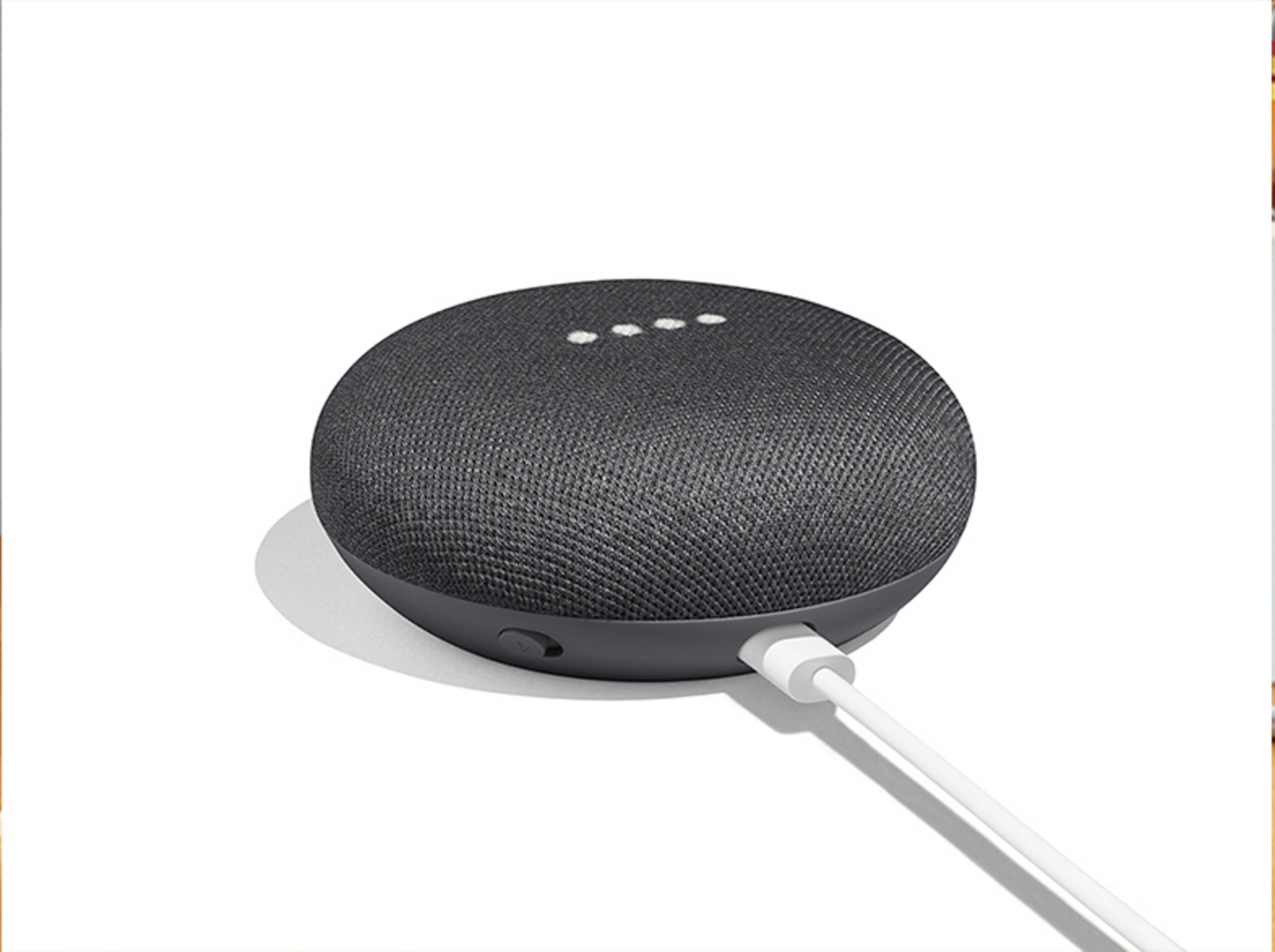 Ein dunkelgrauer Google Nest Mini Lautsprecher mit weißem Ladekabel.