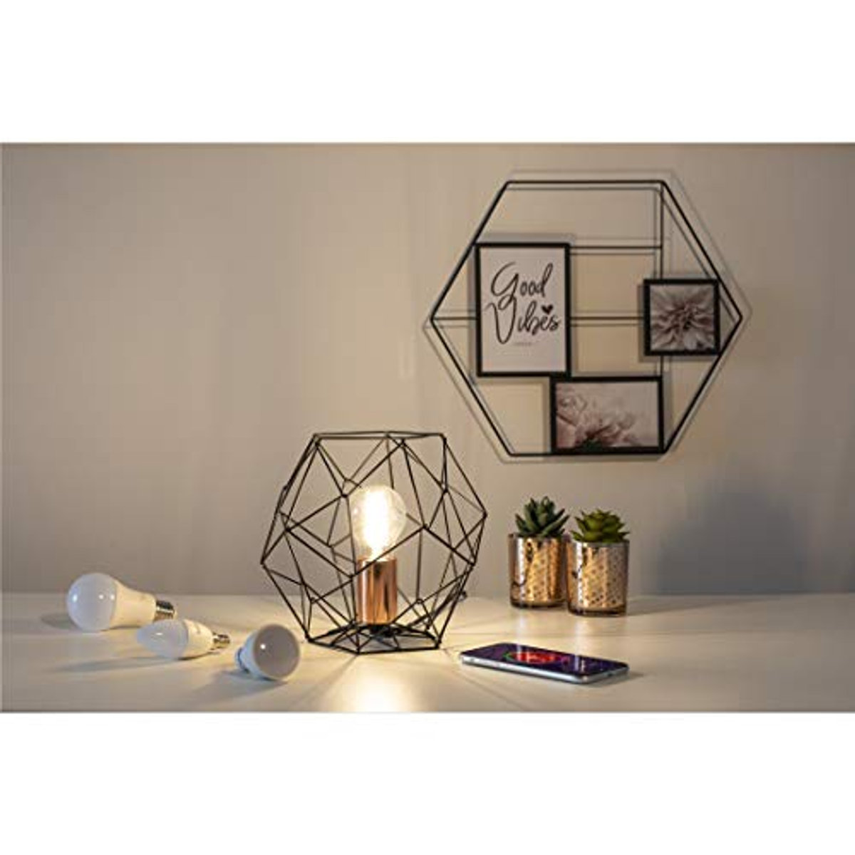 Decoración moderna con lámpara geométrica, bombillas blancas y un teléfono.