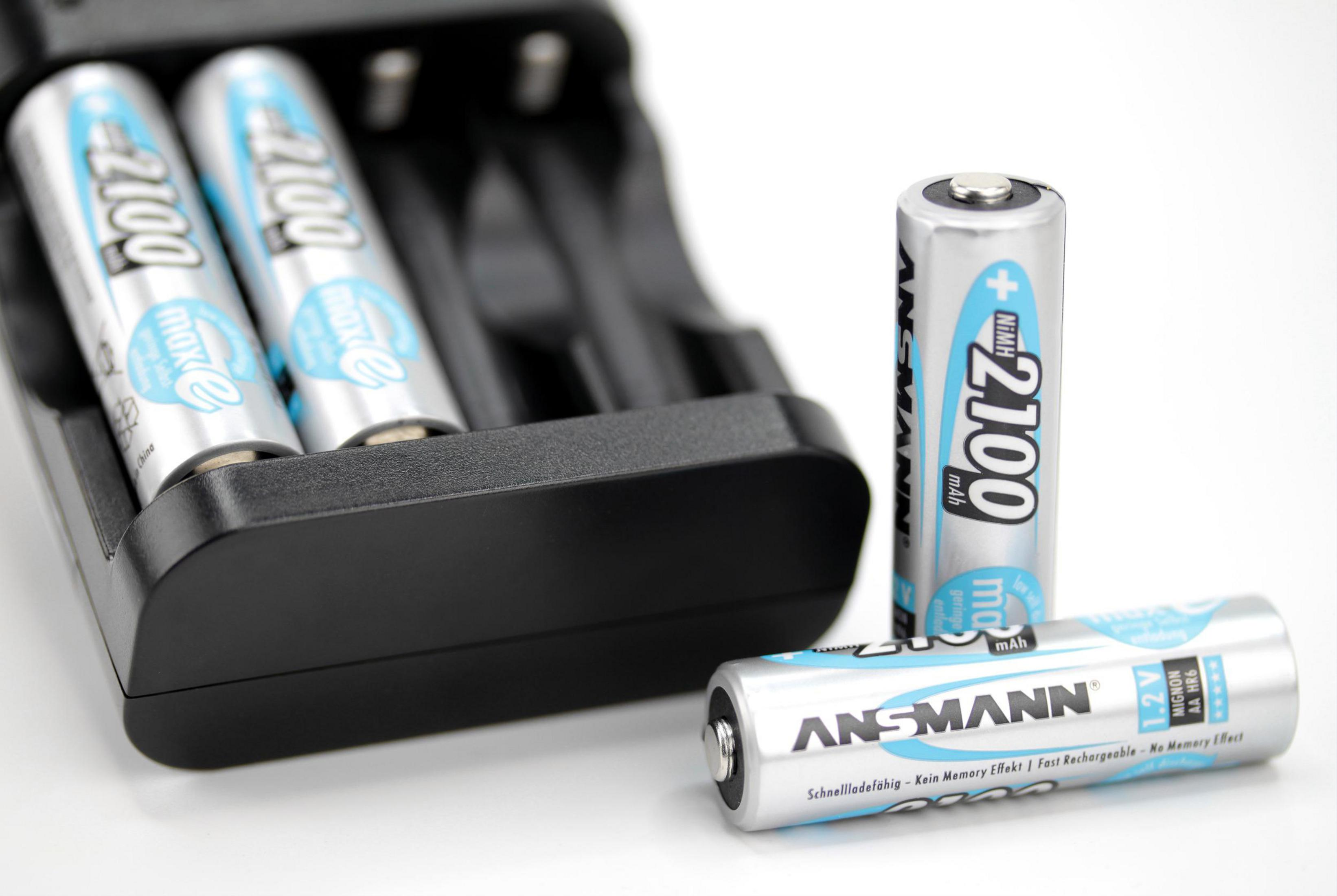 Drei AA-Batterien in einem Ladegerät und zwei AA-Batterien daneben. Die Batterien sind beschriftet.