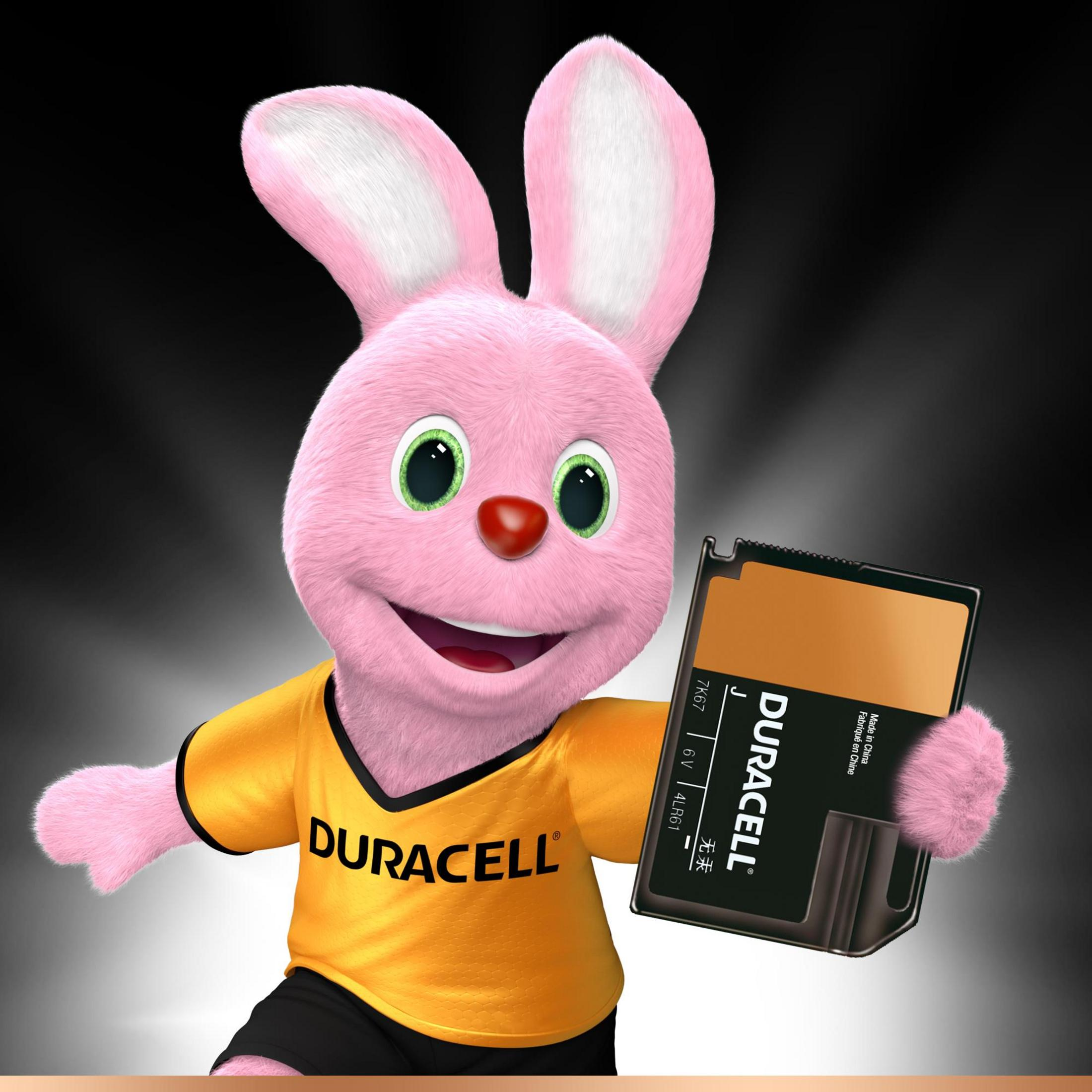 Pinkes Duracell-Häschen hält einen Akku. Es trägt ein gelbes Hemd und lächelt.