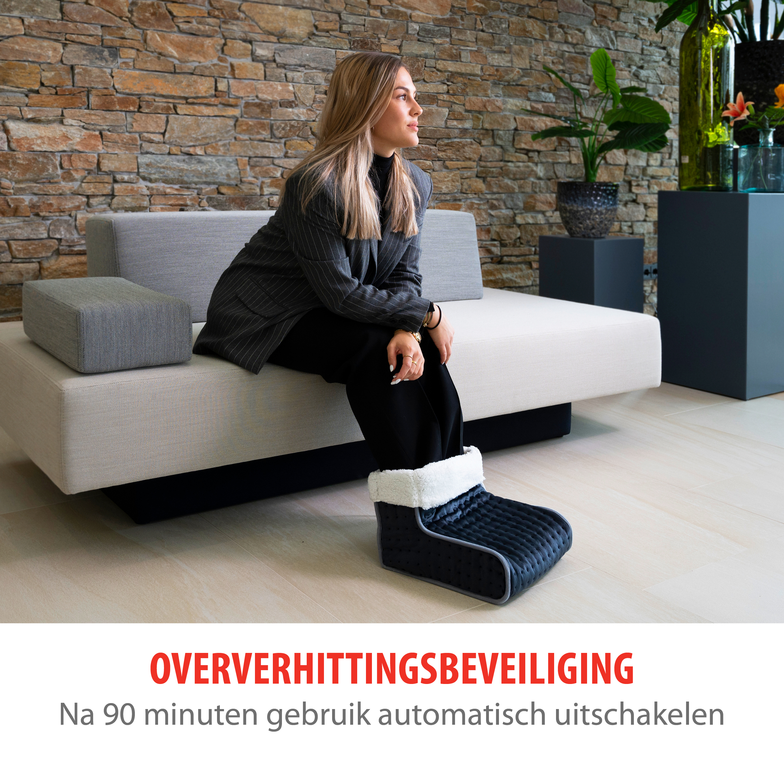Frau mit schwarzer Hose und Blazer, die einen beheizten Stiefel trägt.
