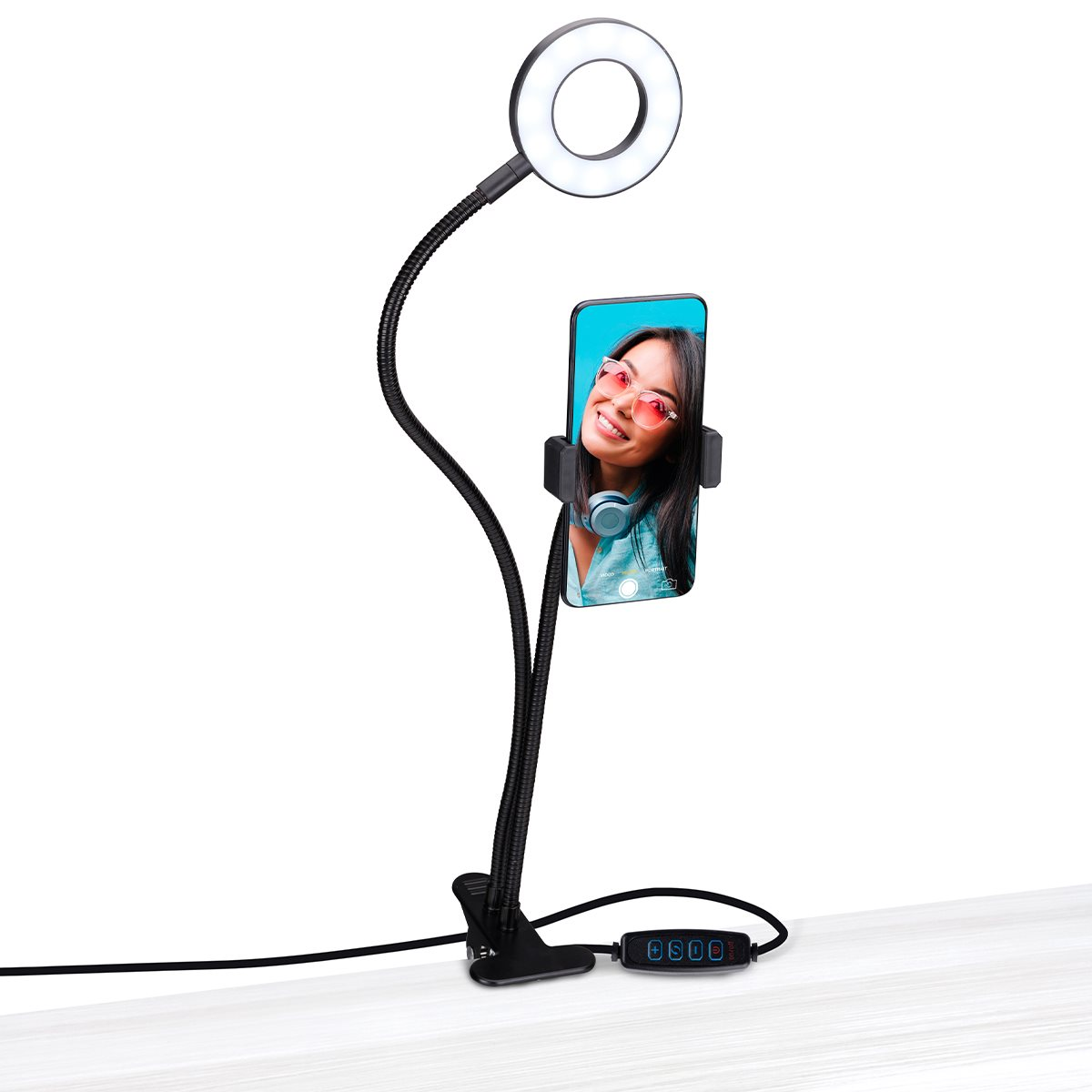 Une lampe annulaire avec un téléphone tenant une femme portant des lunettes de soleil, sur une surface blanche.