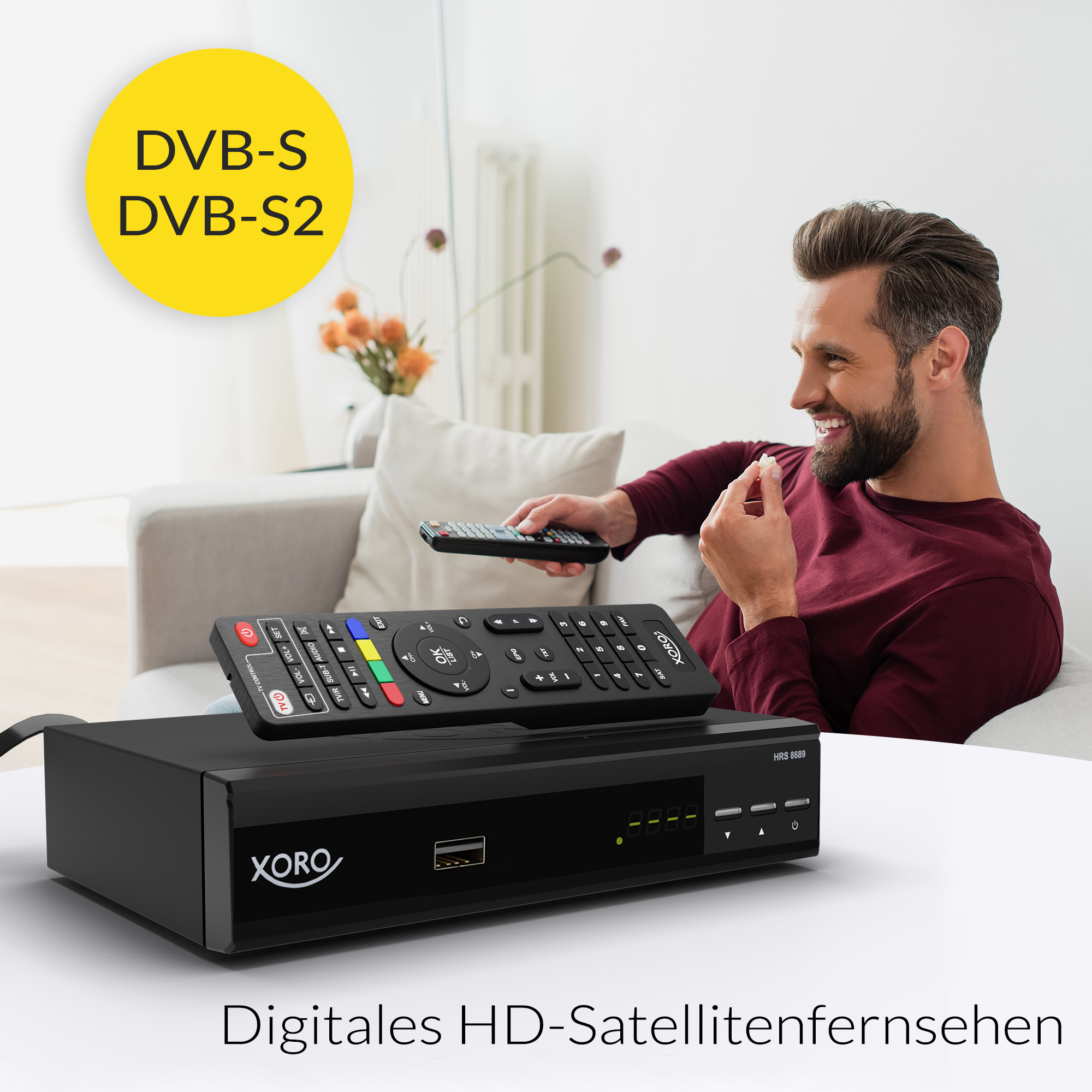 Ein Mann hält eine Fernbedienung. Eine schwarze Xoro-Box steht auf einem Tisch.