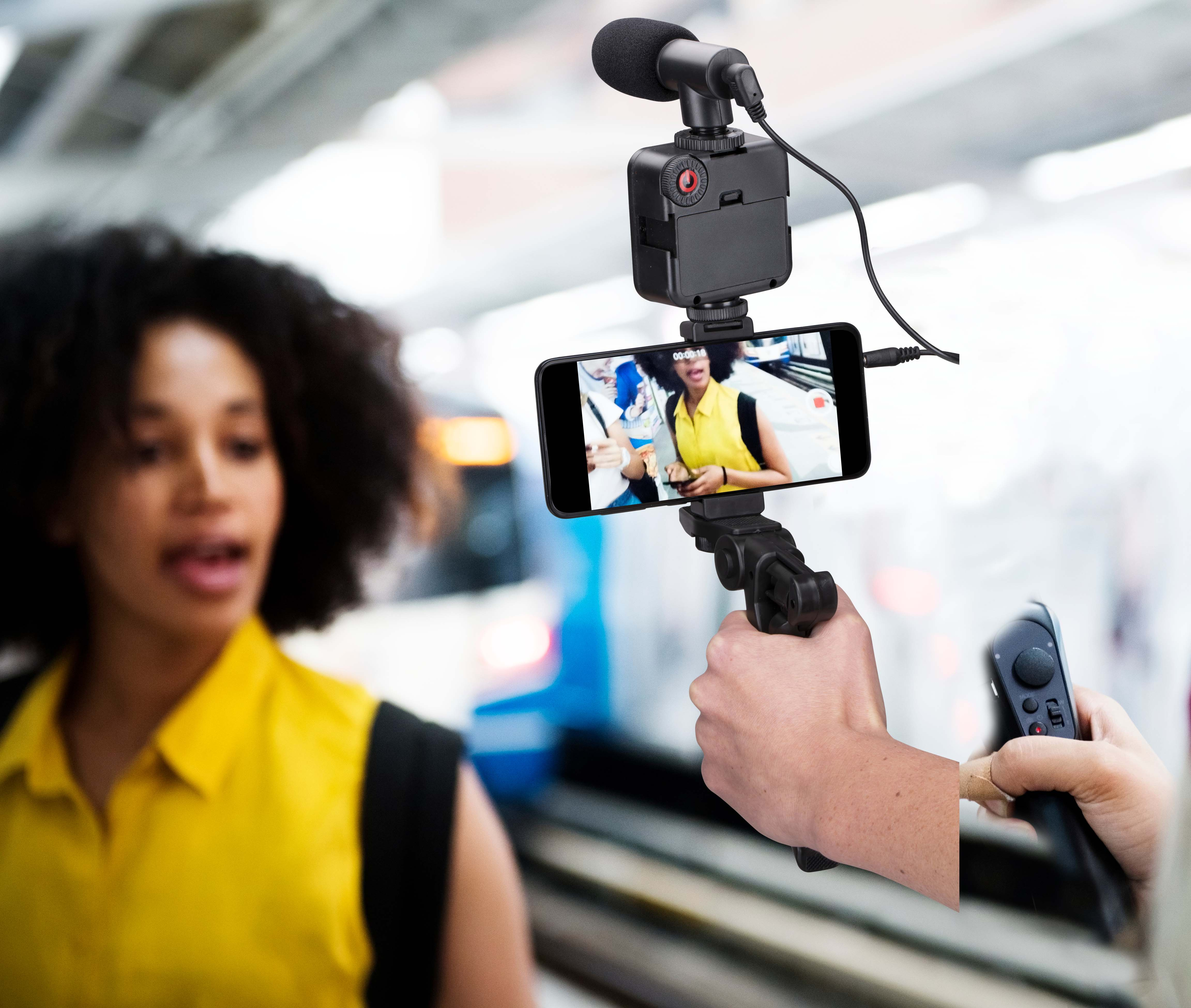 Person holding a phone with a microphone and camera attached.