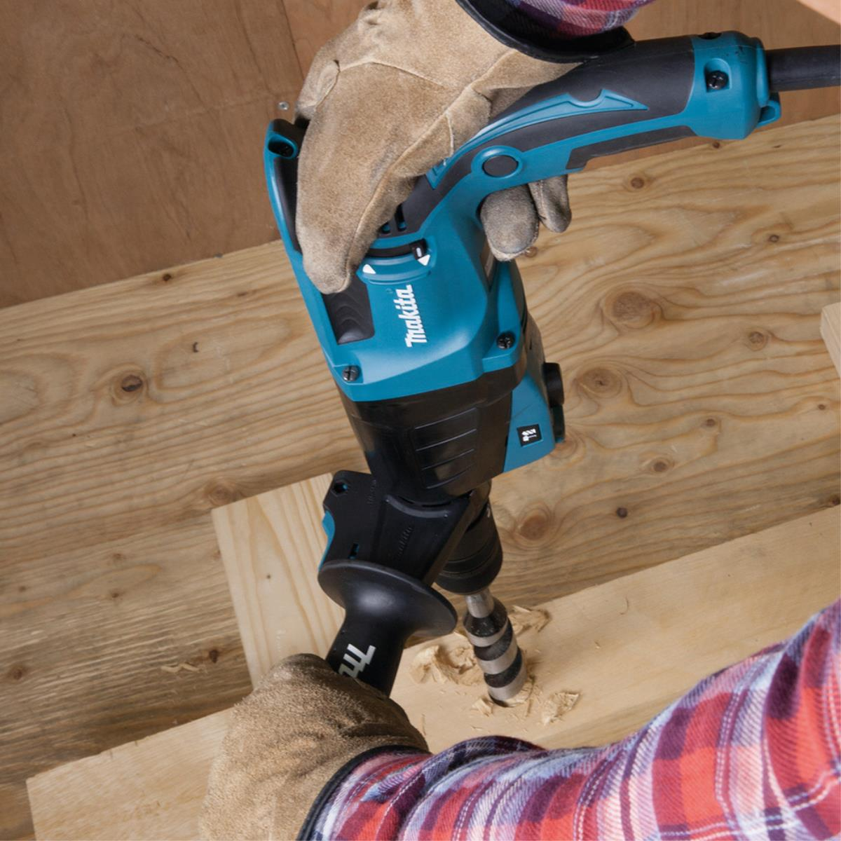 Una persona taladra un agujero en madera con un taladro eléctrico Makita.