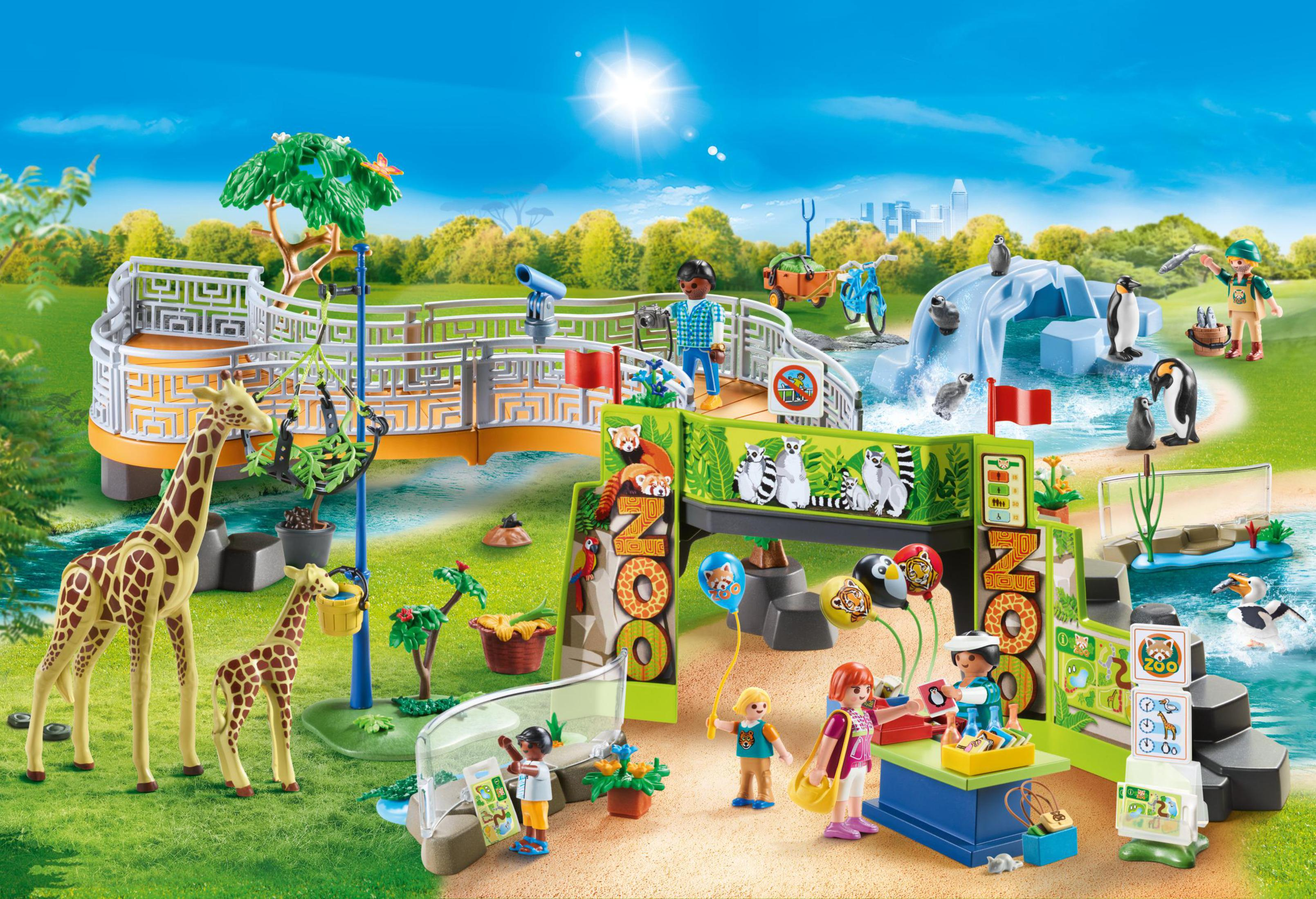 Playmobil-Zoo-Szene mit Tieren, Menschen und Gebäuden unter strahlender Sonne und blauem Himmel.