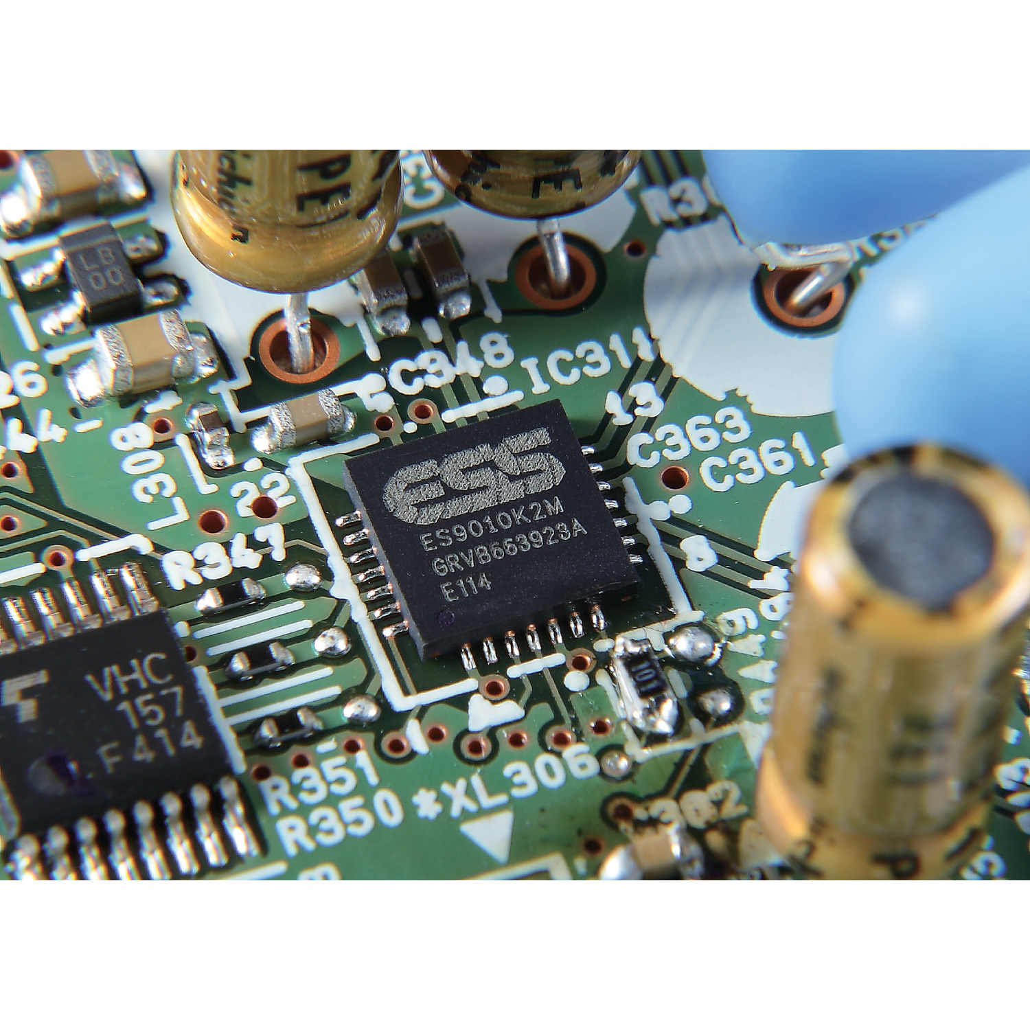 Etiketli bir çip dahil olmak üzere elektronik bileşenlere sahip yeşil bir devre kartının yakın çekimi.