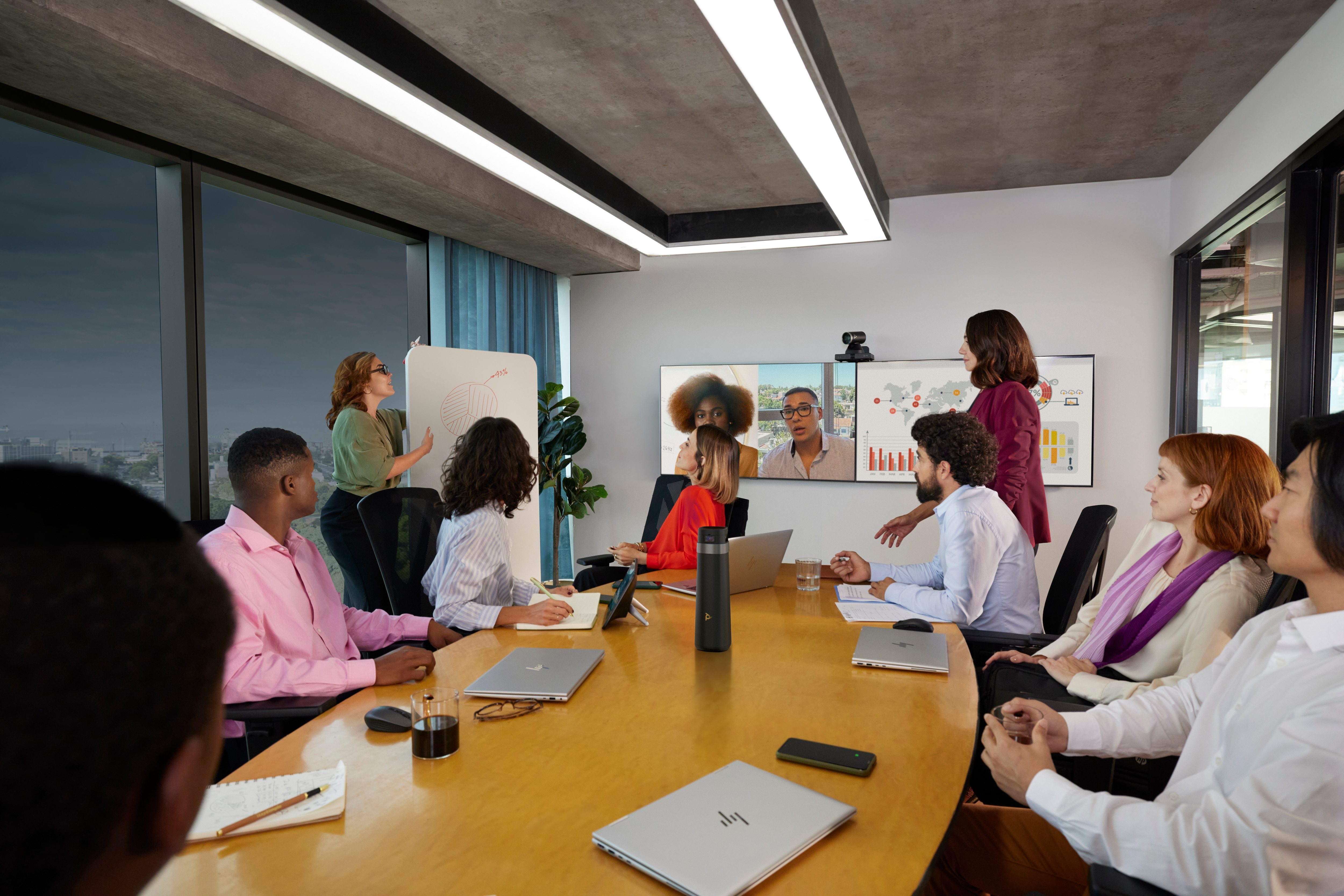 Trwa spotkanie z ludźmi i ekranem pokazującym wideokonferencję.