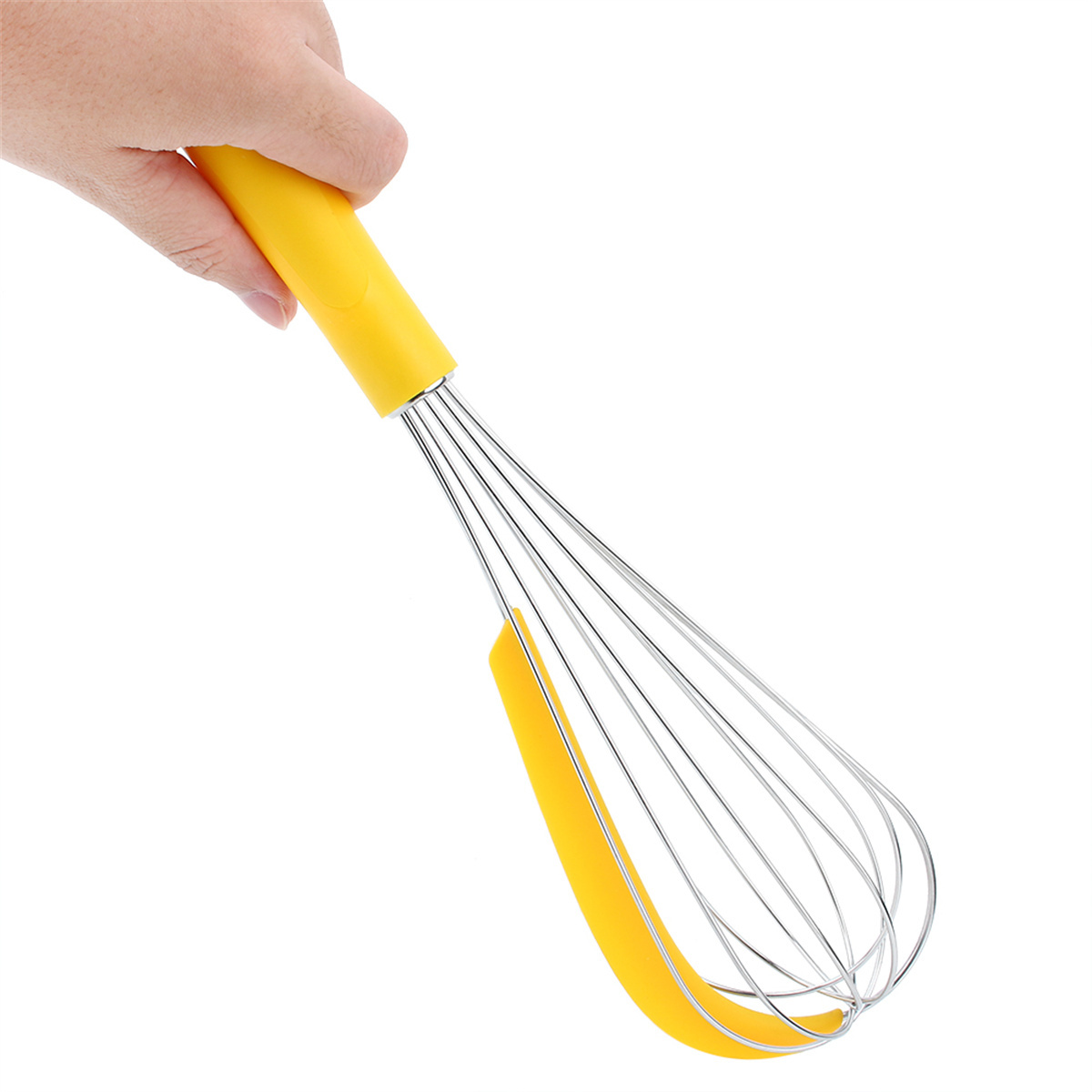 Eine Hand hält einen gelben Schneebesen mit einem gelben Silikon-Schaber, isoliert auf Weiß.