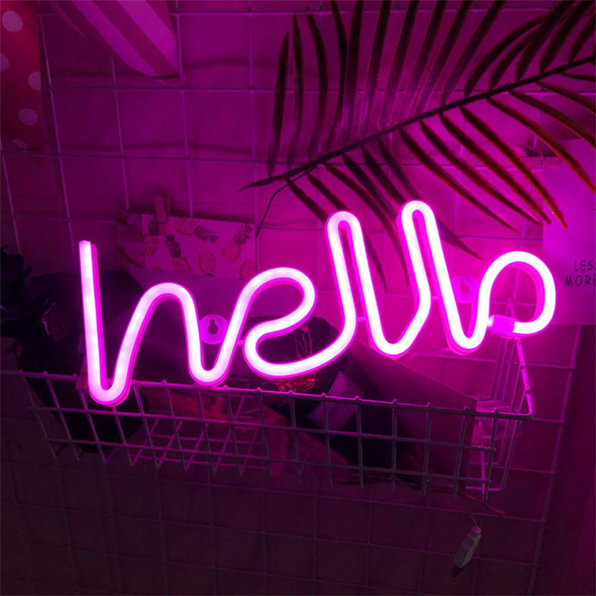 Pinkes Neonzeichen mit 'hello', montiert an Drahtkorb, an pinker Wand.