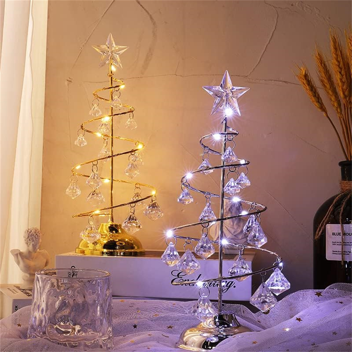 Zwei Weihnachtsbaumdekorationen. Eine goldene, eine silberne, mit Lichtern und Sternspitzen.