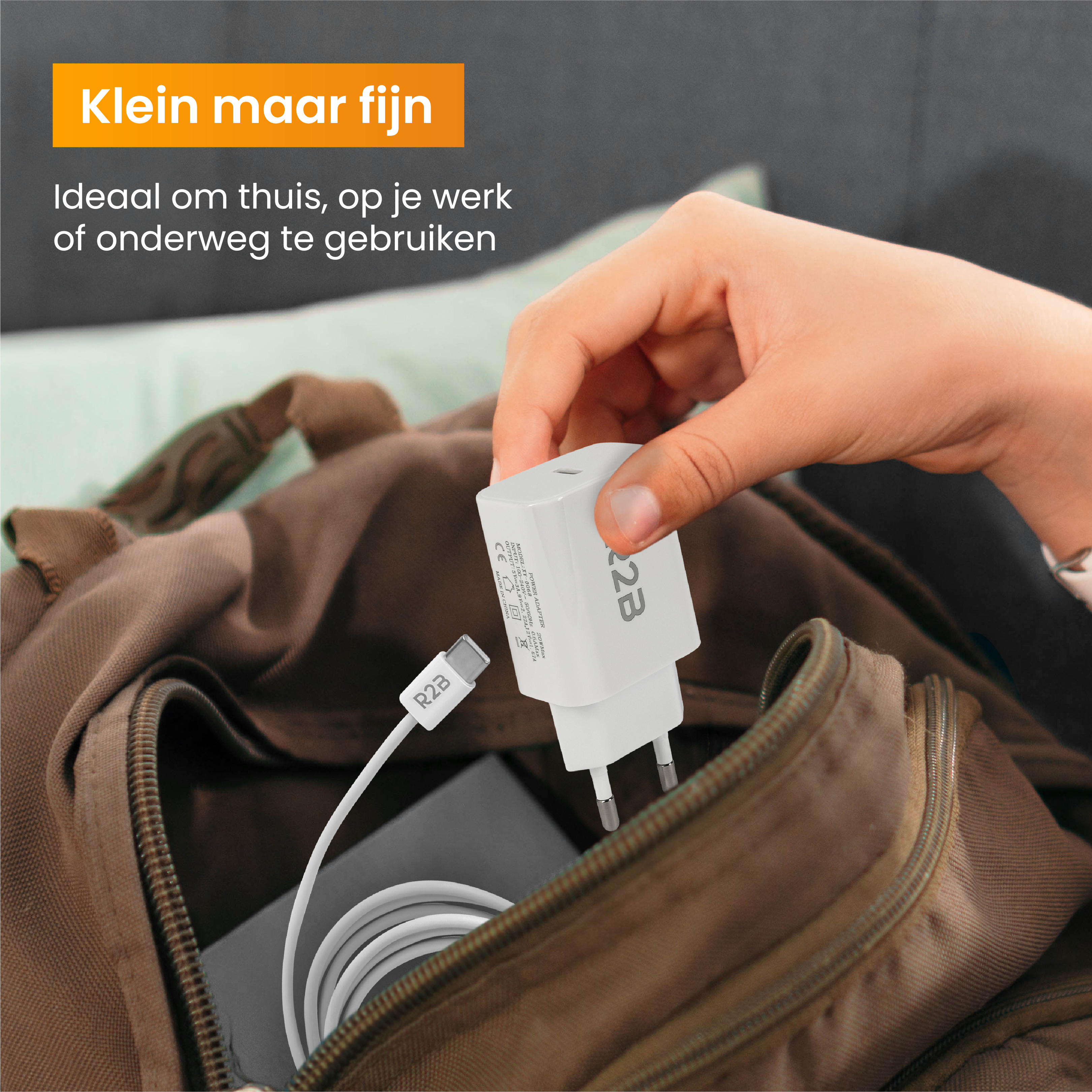 Eine Hand nimmt ein weißes Ladegerät aus einer braunen Tasche. Das Ladegerät ist mit R2B beschriftet.