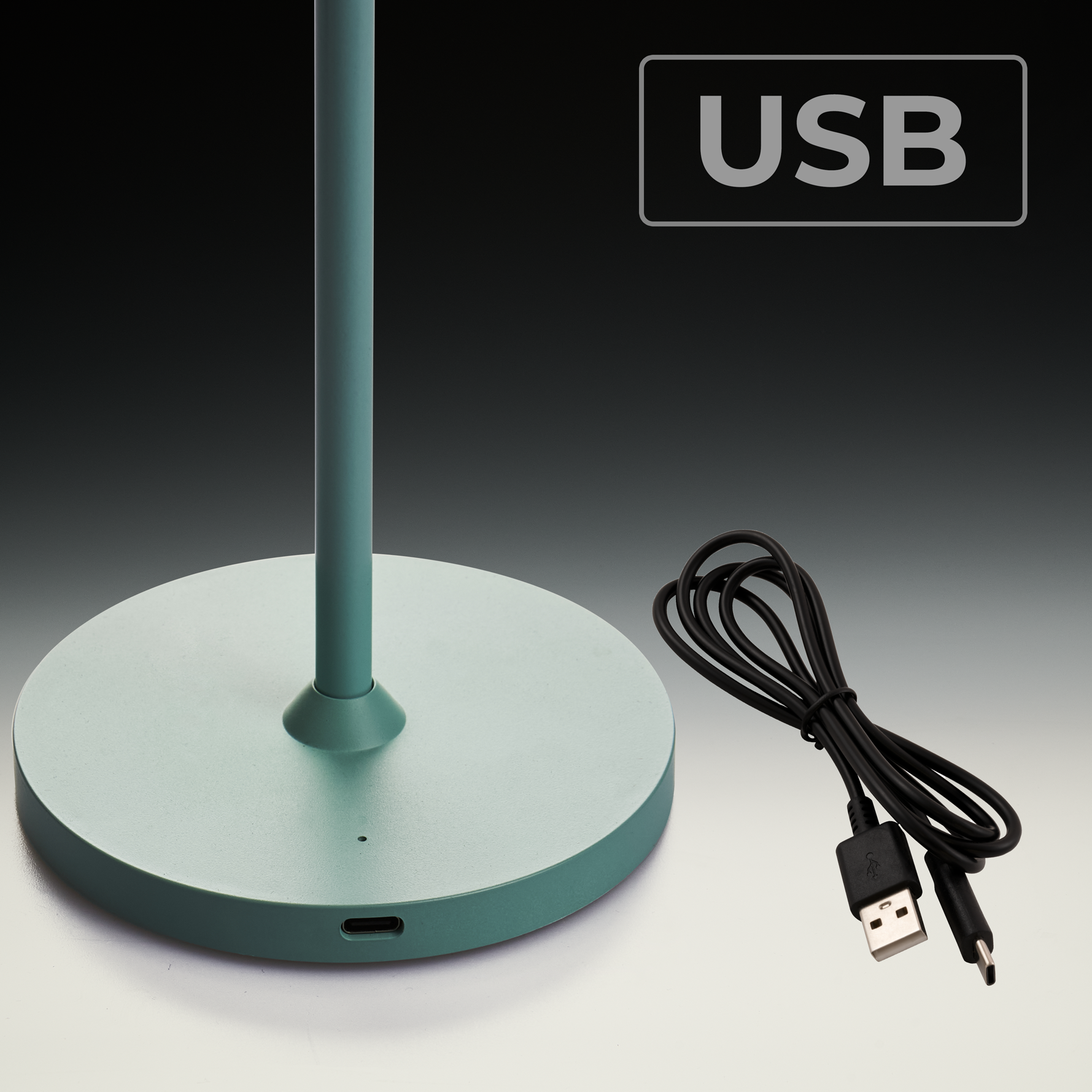 Grüne Basis und Stange einer Lampe. Ein USB-Kabel liegt auf dem Tisch.