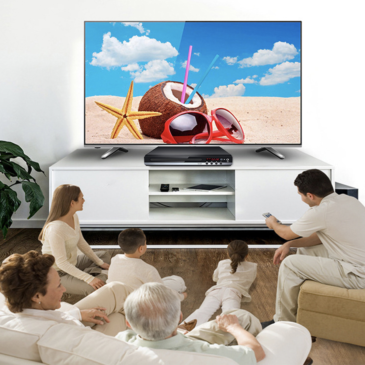 Familie schaut fern, eine Kokosnuss und Sonnenbrille liegen auf dem Fernseher.