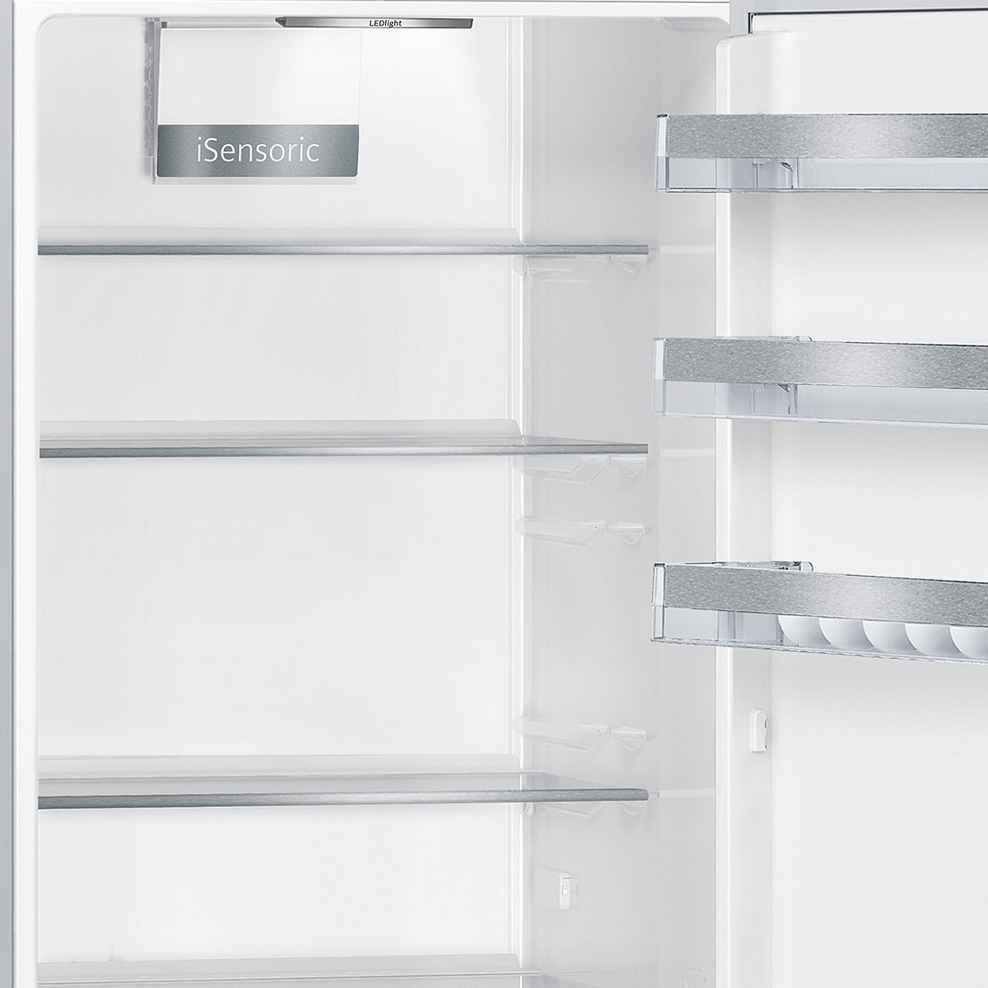 Offener, leerer Kühlschrank mit Regalen. Ein weißer Innenraum mit Metallverkleidung, iSensoric-Etikett und LED-Licht.