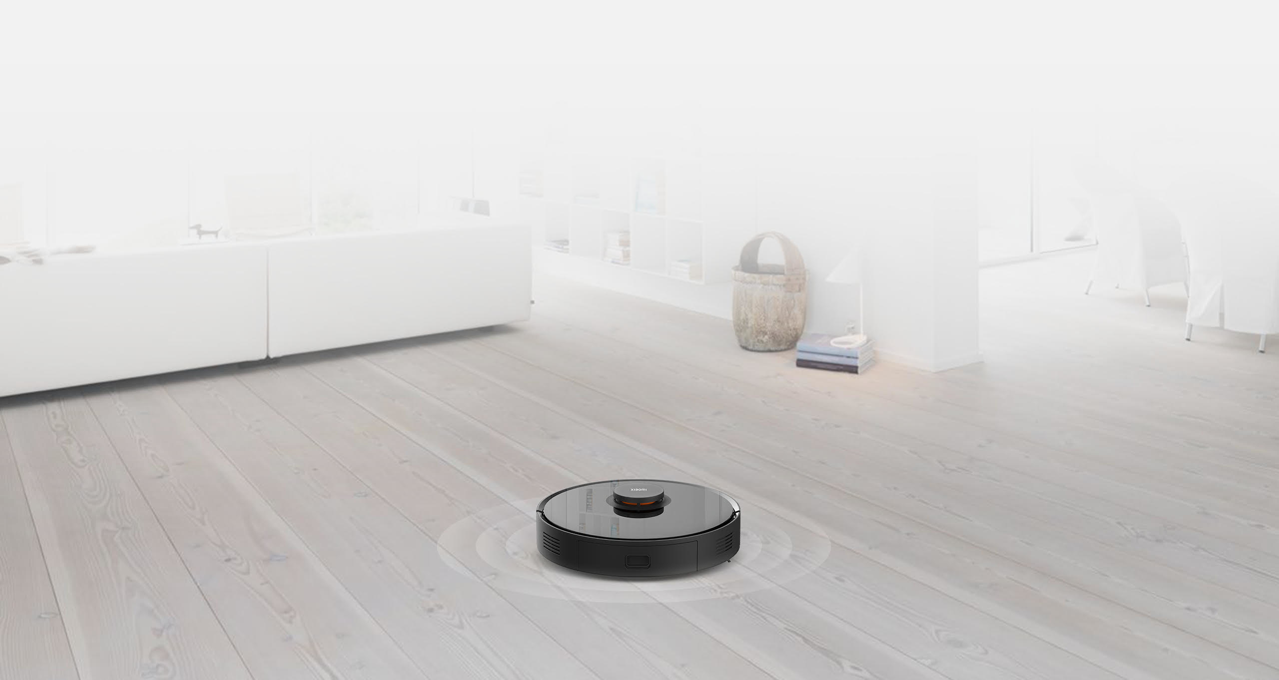 Ahşap zeminde siyah robot süpürge. Yumuşak odaklı beyaz arka plan.
