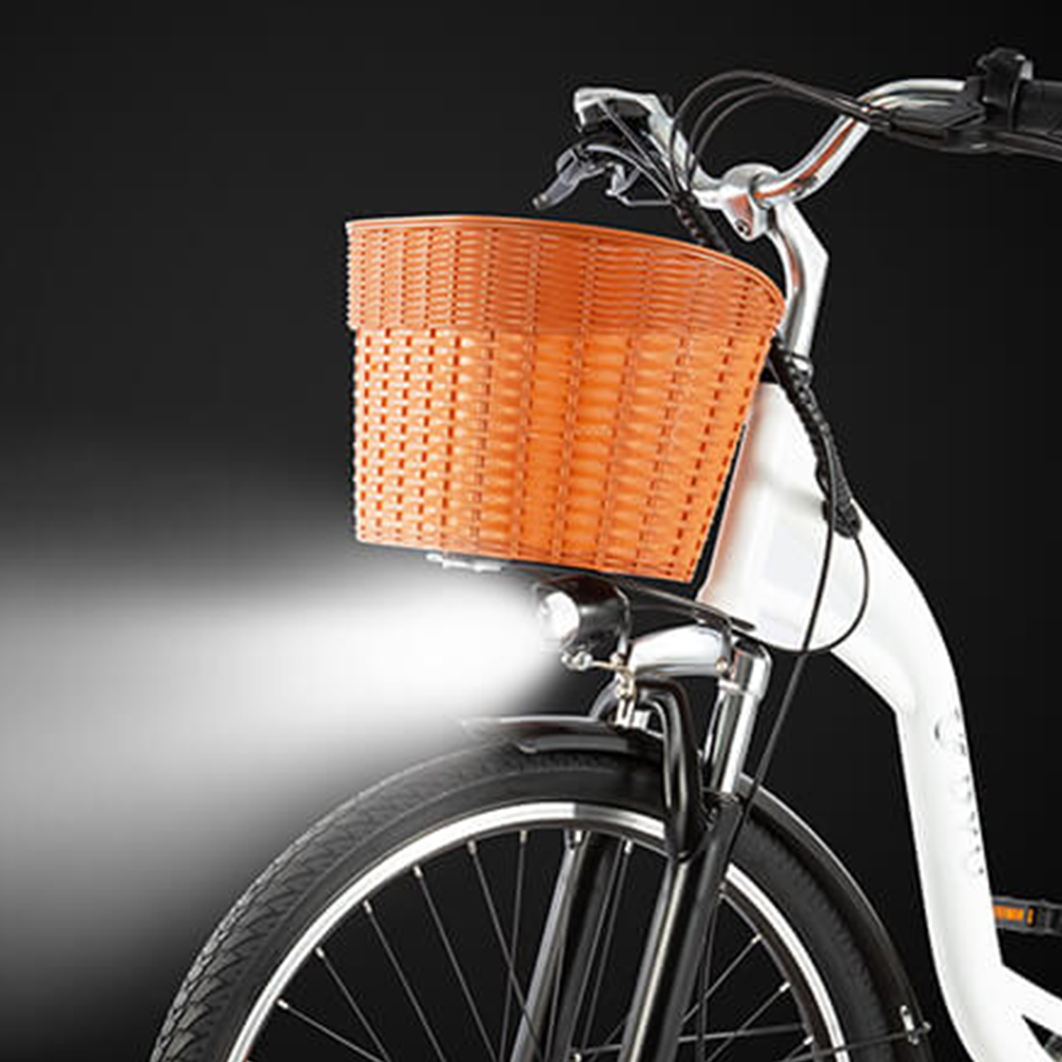 Biały rower z pomarańczowym koszem i jasnym reflektorem świecącym do przodu.