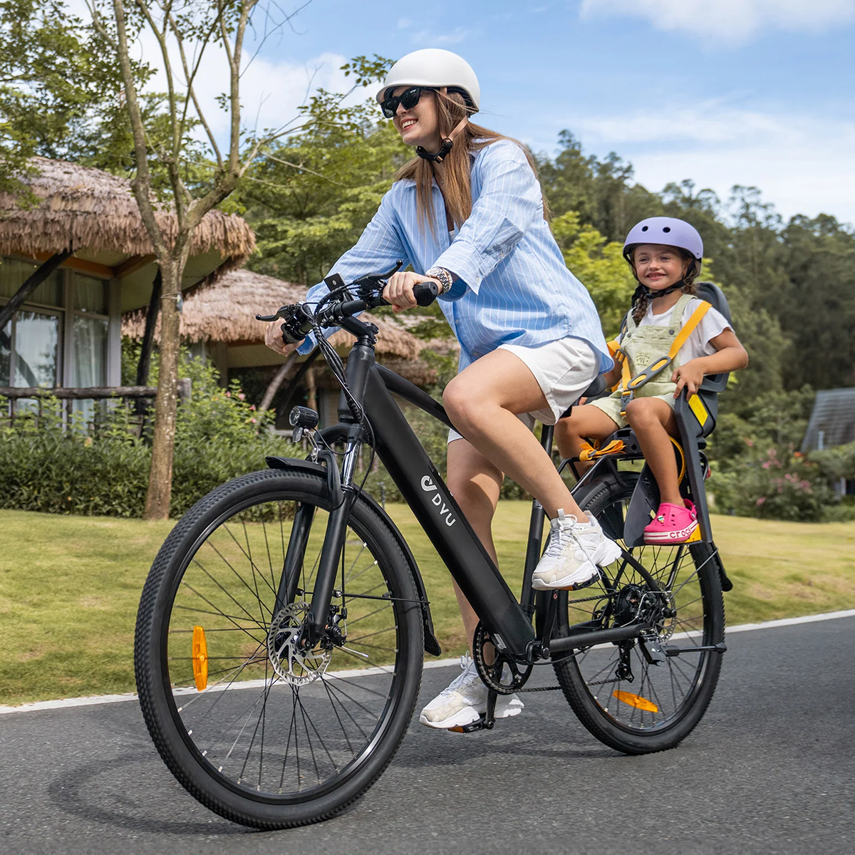 Kobieta i dziecko jadą na czarnym rowerze BYKU na zewnątrz. Oboje noszą kaski.