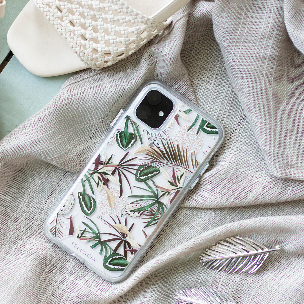Une coque de téléphone avec un motif floral sur une surface neutre et texturée. Une paire de sandales en arrière-plan.