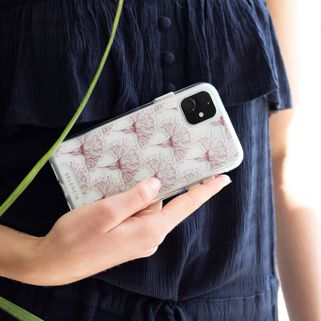 Une femme tient un téléphone avec une coque transparente à motif de fleurs rouges.