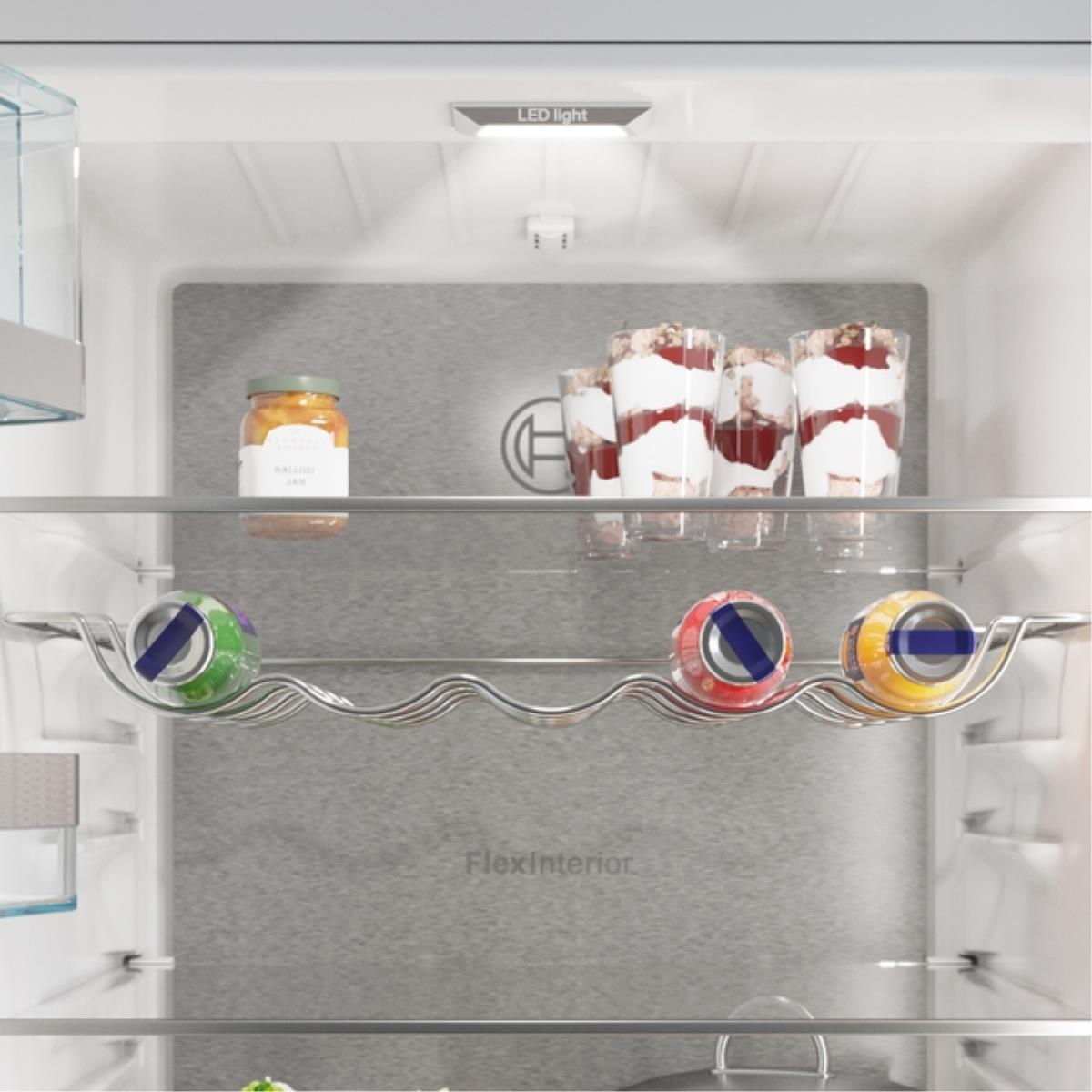 Im Kühlschrank befinden sich Gläser, Desserts und Getränke auf den Regalen. Der Kühlschrank ist weiß mit grauen Akzenten.