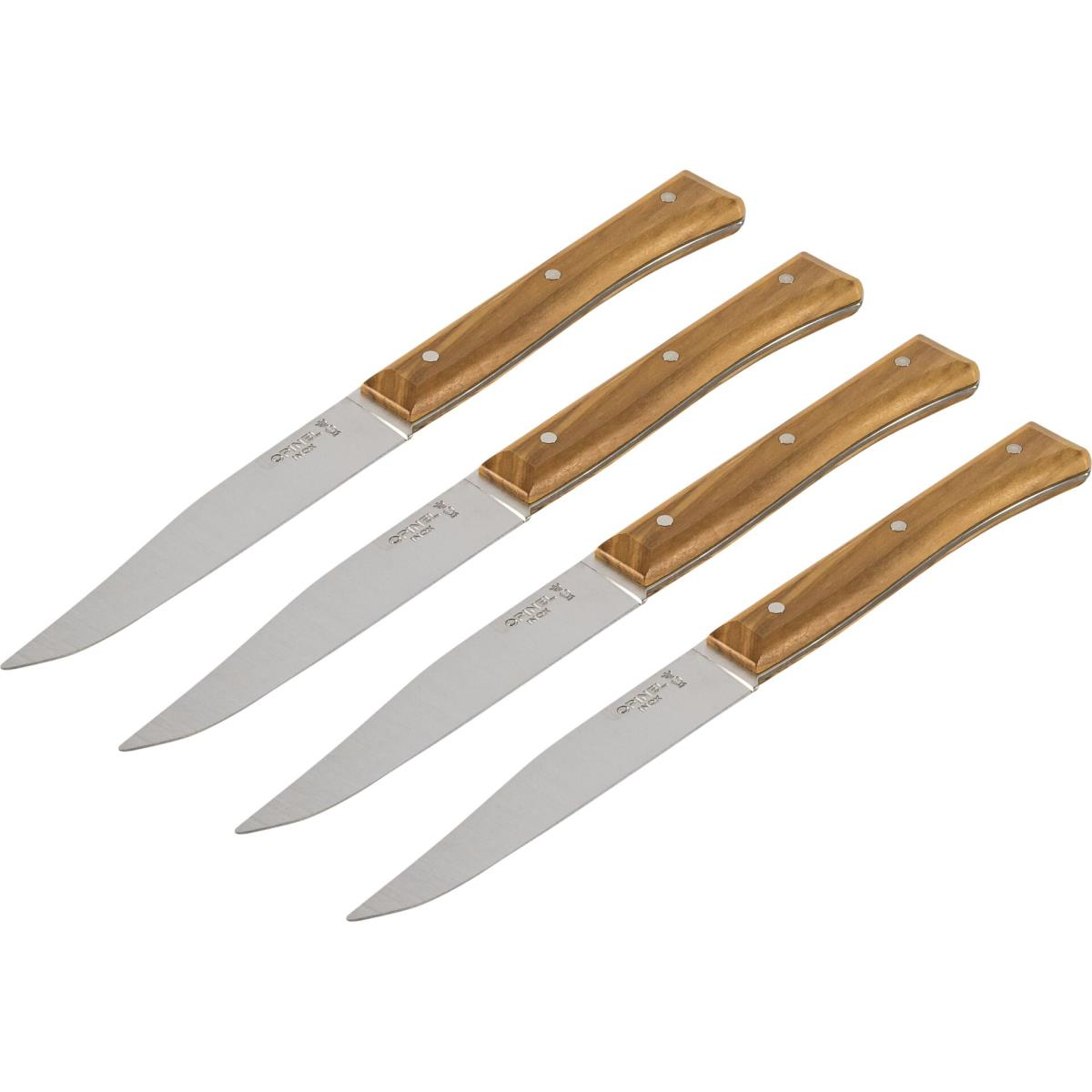 Quattro coltelli da bistecca con manici in legno, su sfondo bianco.