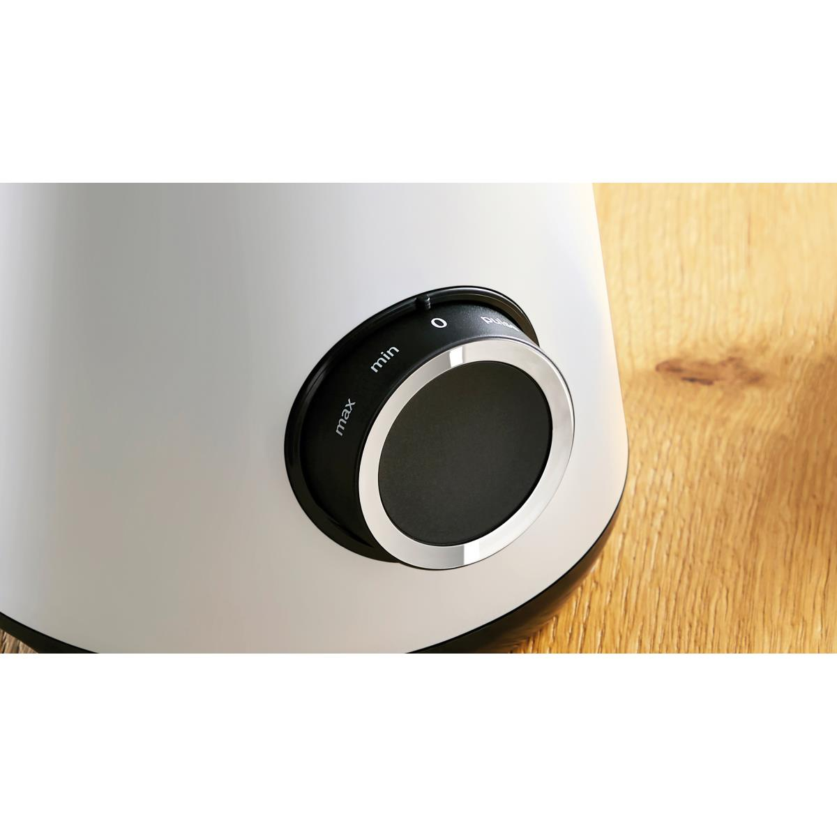 Białe urządzenie elektryczne z czarnym pokrętłem i drewnianym stołem w tle.