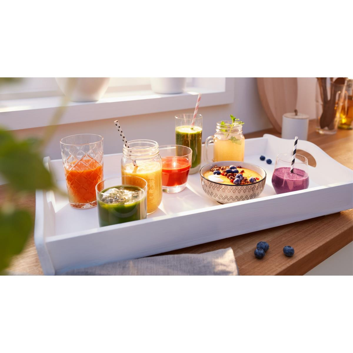 Taca z różnymi koktajlami i miską jagód na drewnie, blisko okna.