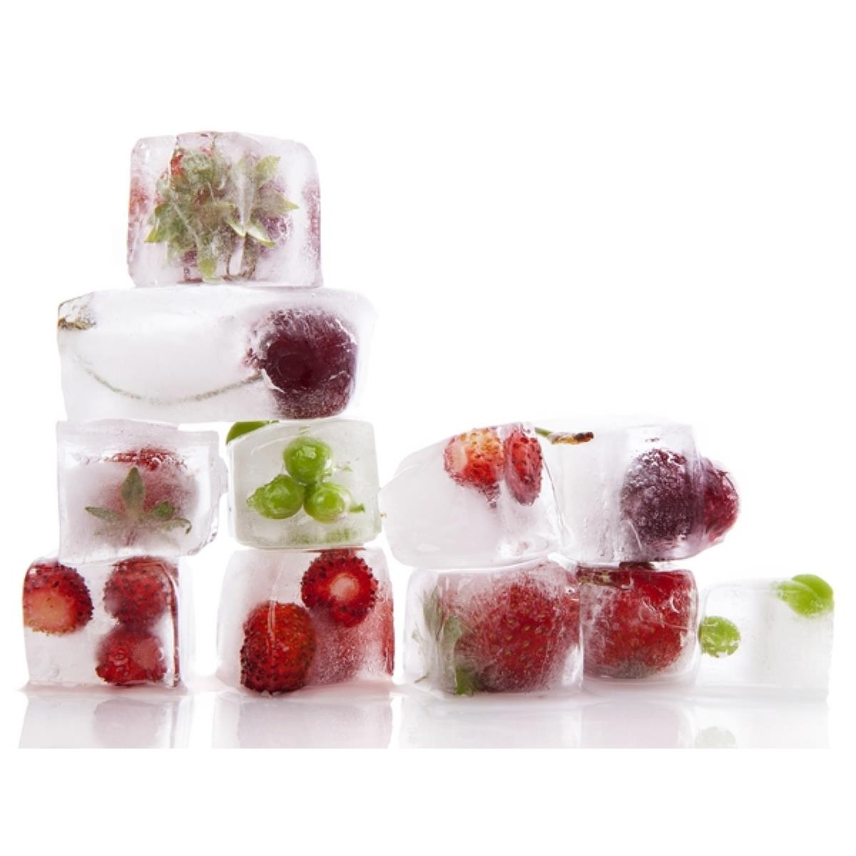 Eiswürfel mit gefrorenen Beeren und Grünzeug, angeordnet auf weißem Hintergrund.