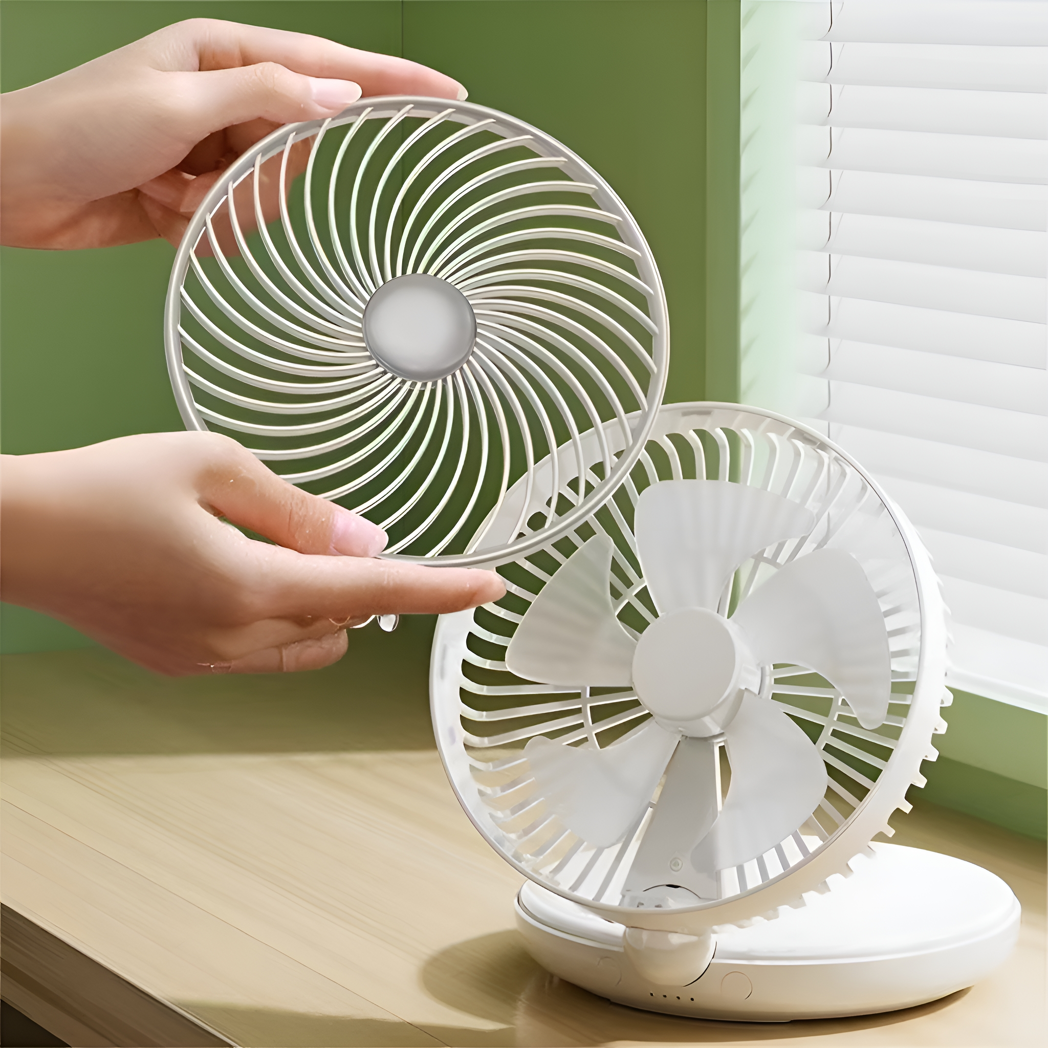 Ein kleiner weißer Ventilator. Eine Hand hält die vordere Schutzabdeckung vom Ventilator weg.