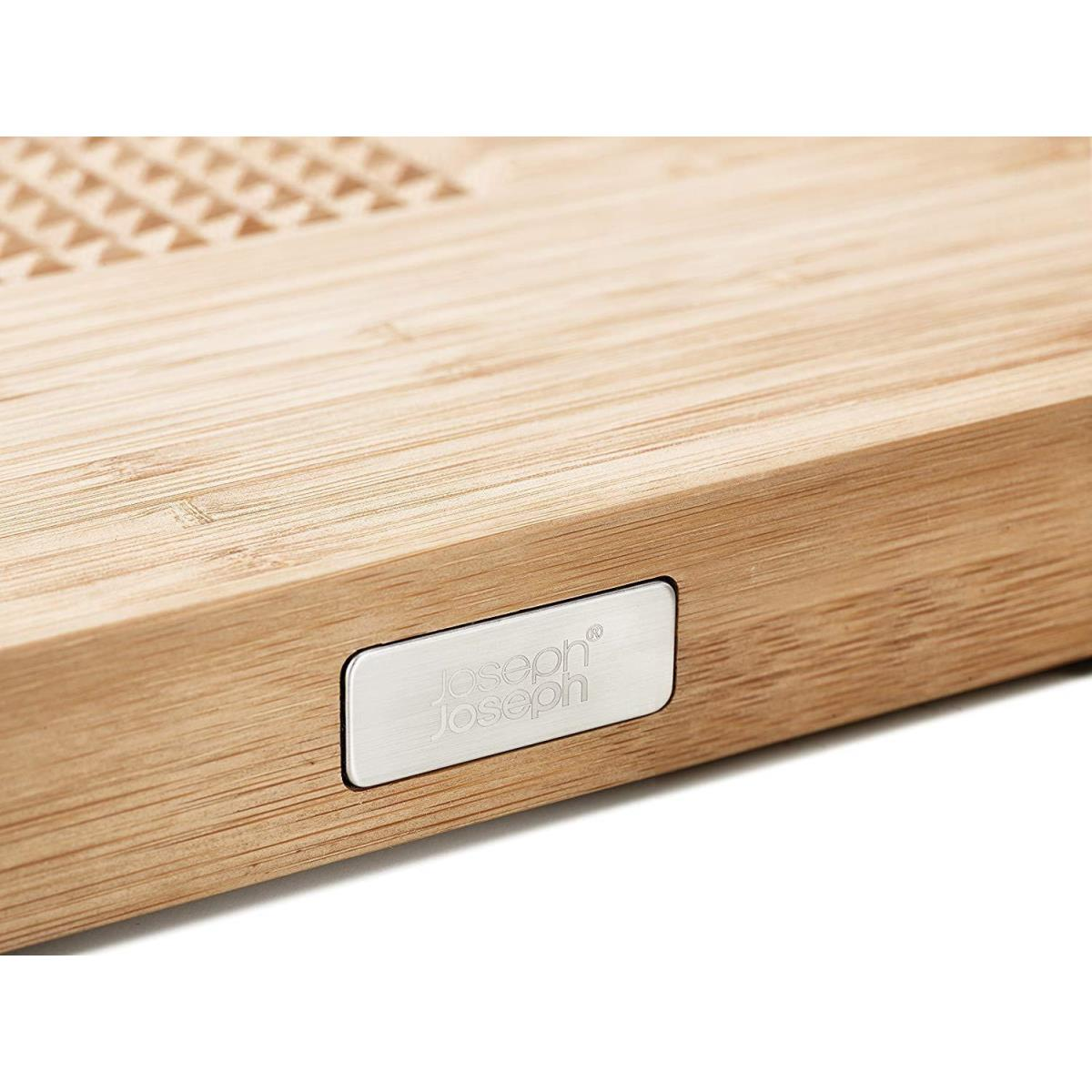 Nahaufnahme eines Holzschneidebretts mit silbernem Logo. Das Brett hat eine Bambusstruktur.