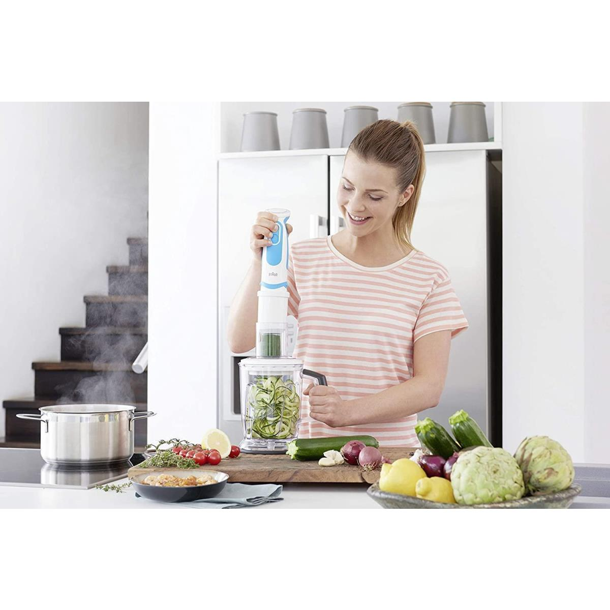 Mujer usa un espiralizador de vegetales con ingredientes frescos en una tabla de madera.
