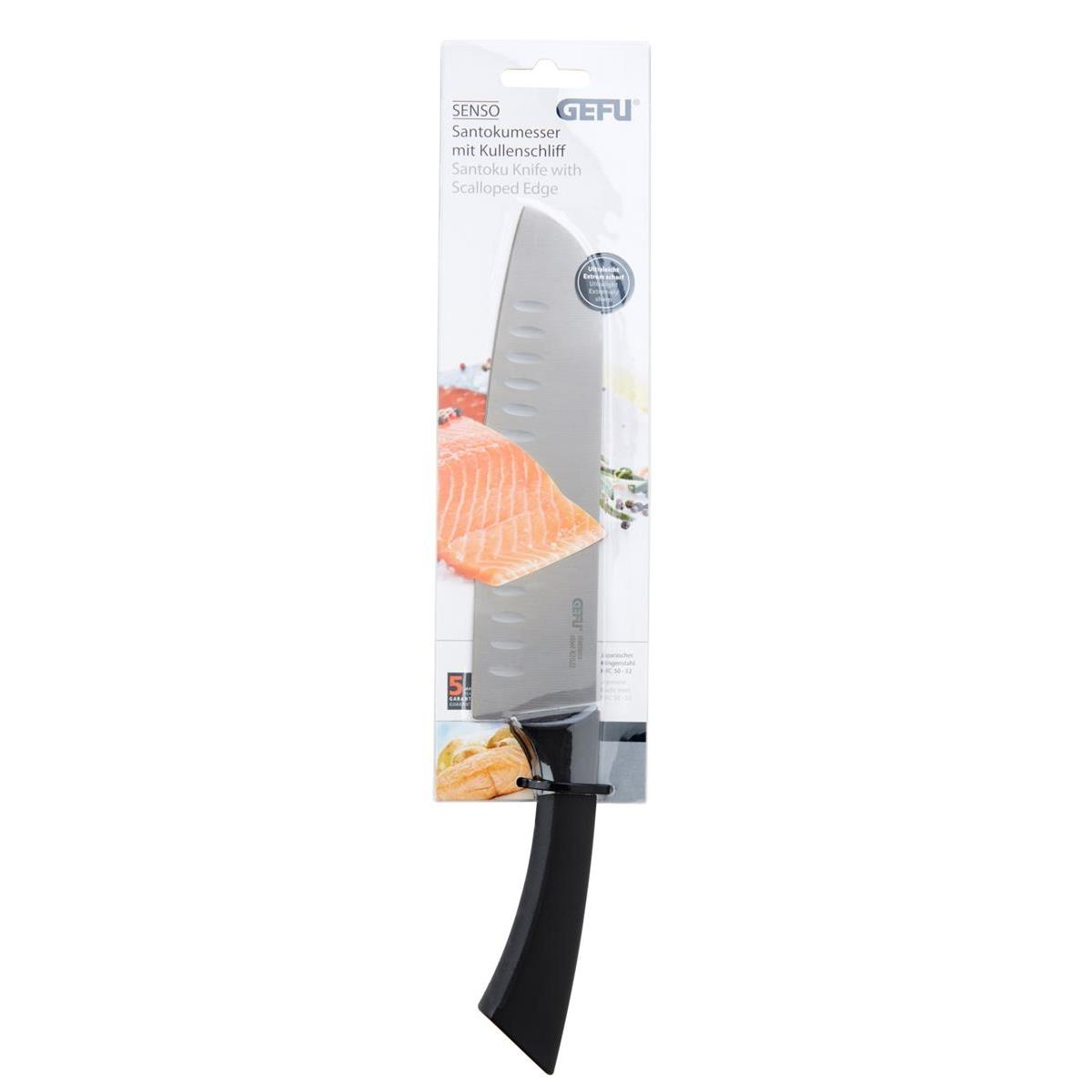 Ein Santoku-Messer mit Wellenschliff in seiner Verpackung, mit einer Lachsscheibe.