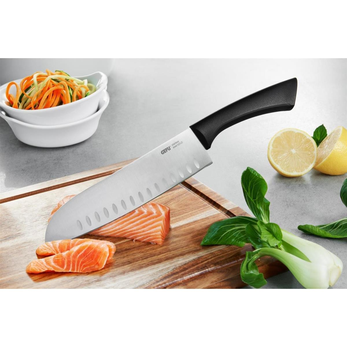 Küchenmesser auf einem Holzbrett, das Lachs schneidet. Gemüse im Hintergrund.