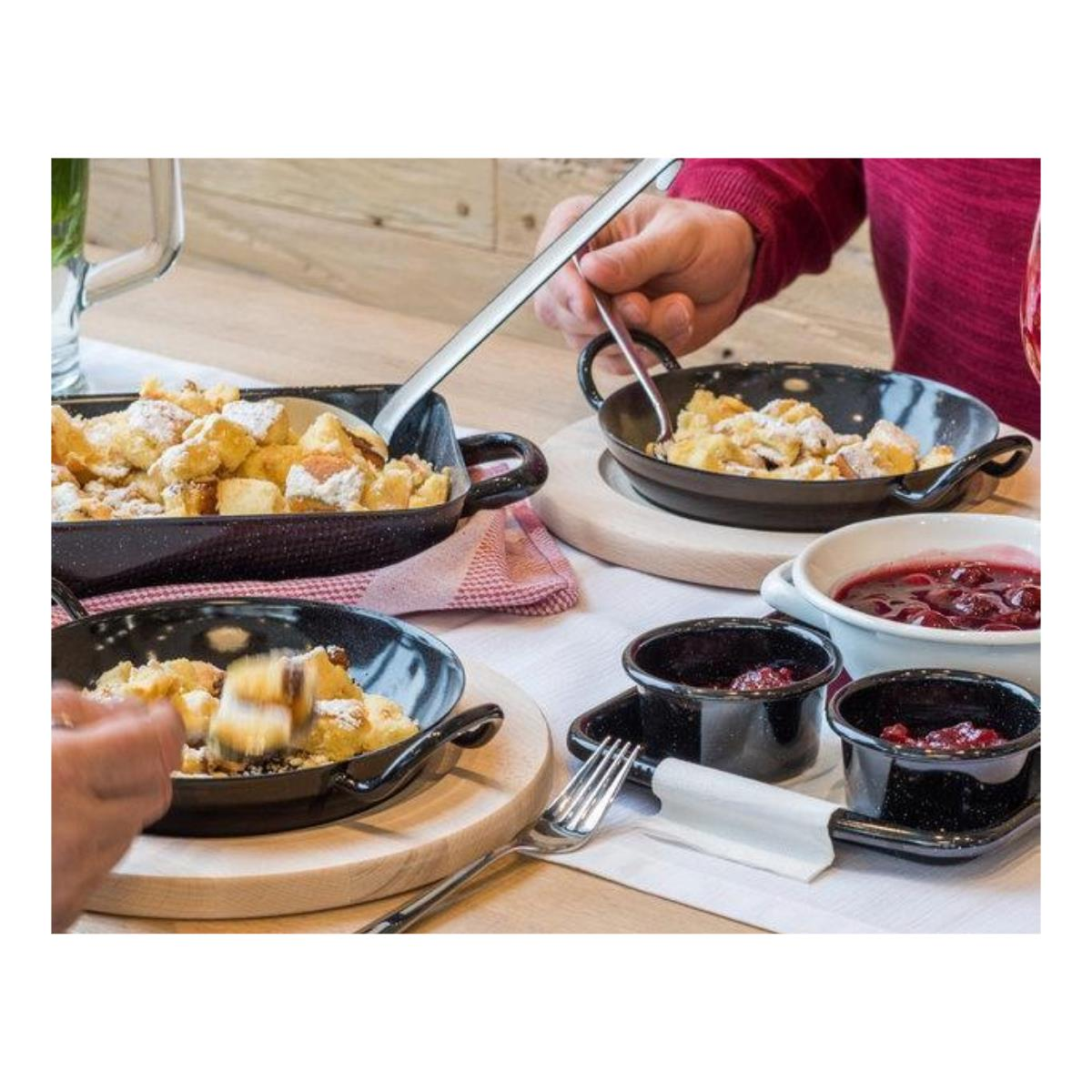 Essen in schwarzen Pfannen auf Holzbrettern, serviert mit Soßen.