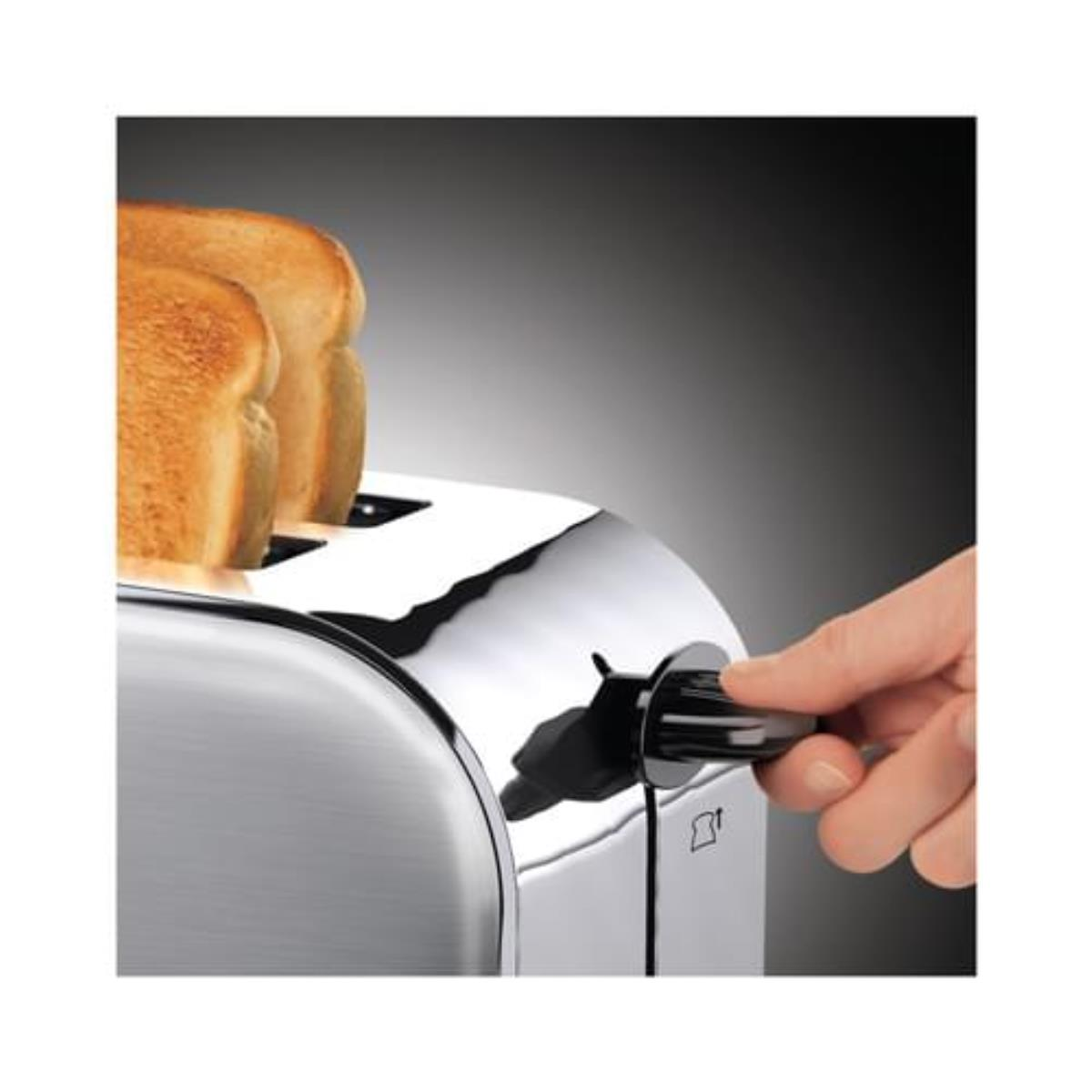 Ręka obracająca pokrętło w chromowanym tosterze z dwoma kromkami tostowanego chleba.
