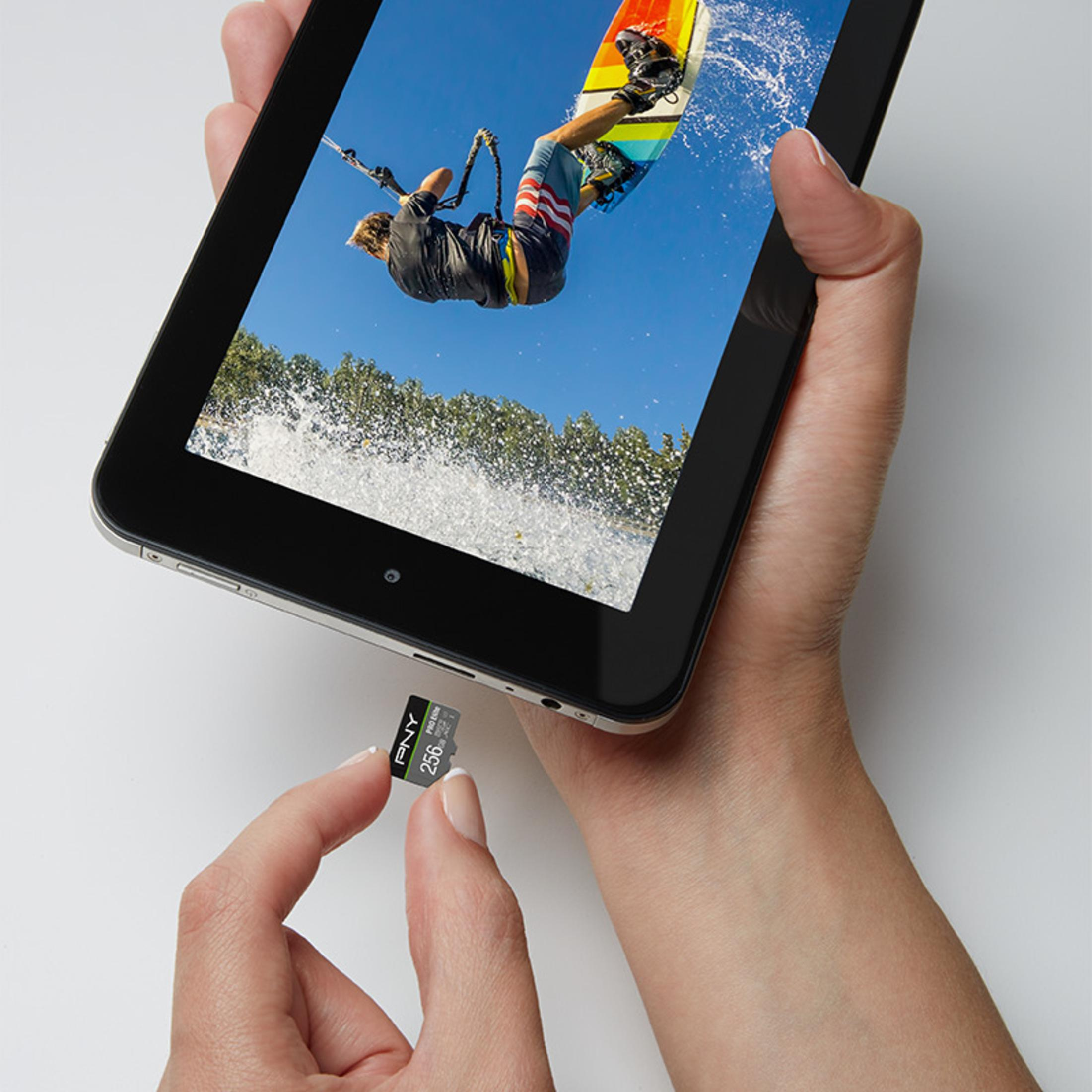Mani che tengono un tablet che mostra una persona che fa kitesurf, con una scheda di memoria nera.
