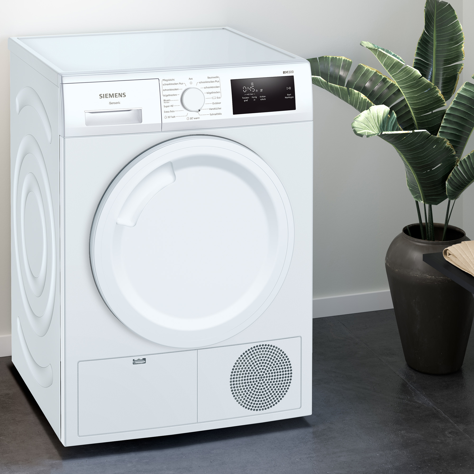 Ein weißer Siemens-Trockner mit digitaler Anzeige. Im Hintergrund steht eine Topfpflanze.