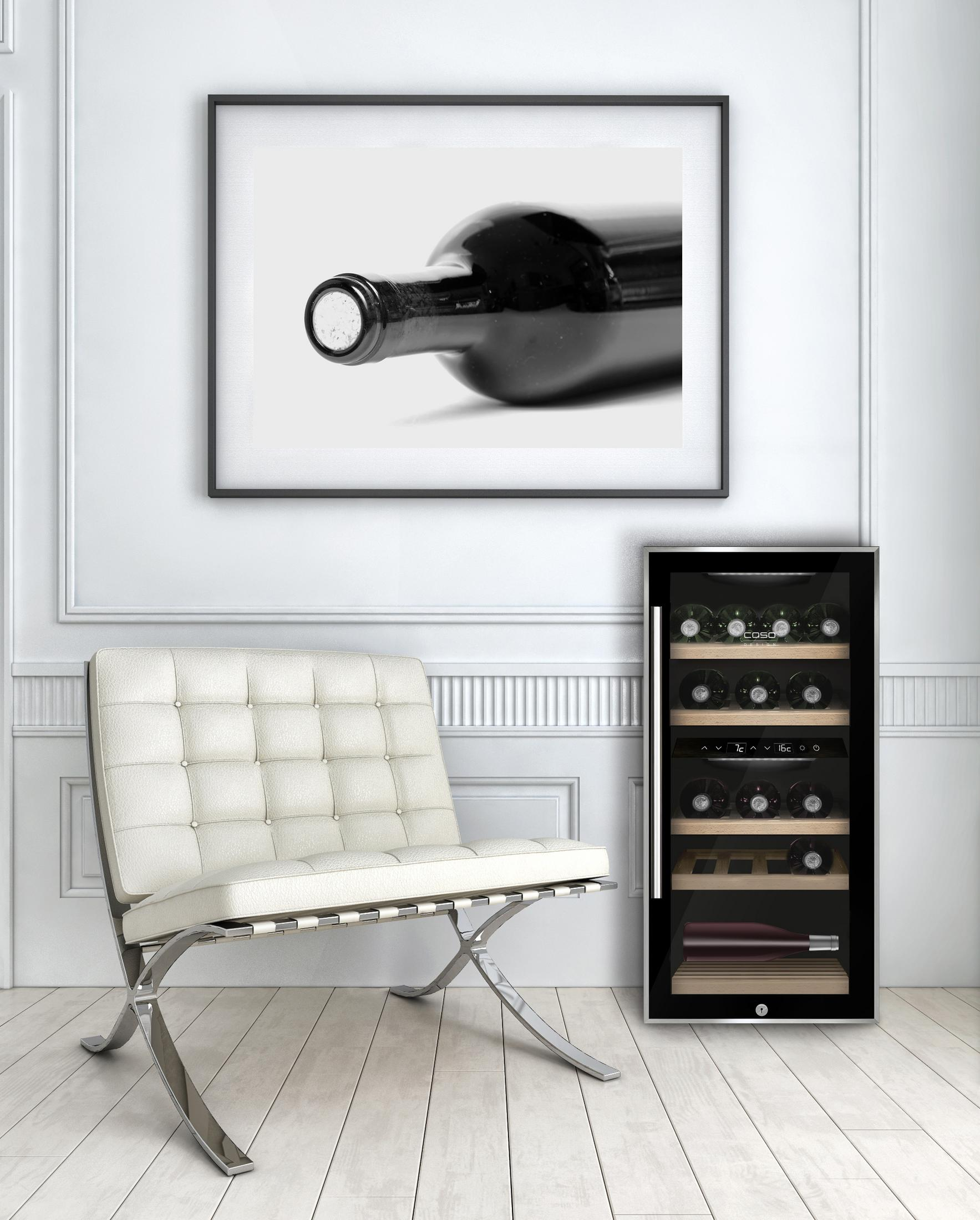 Wein liegende Flasche vor Weinkühler. Schwarzer und weißer Kunstdruck darüber.